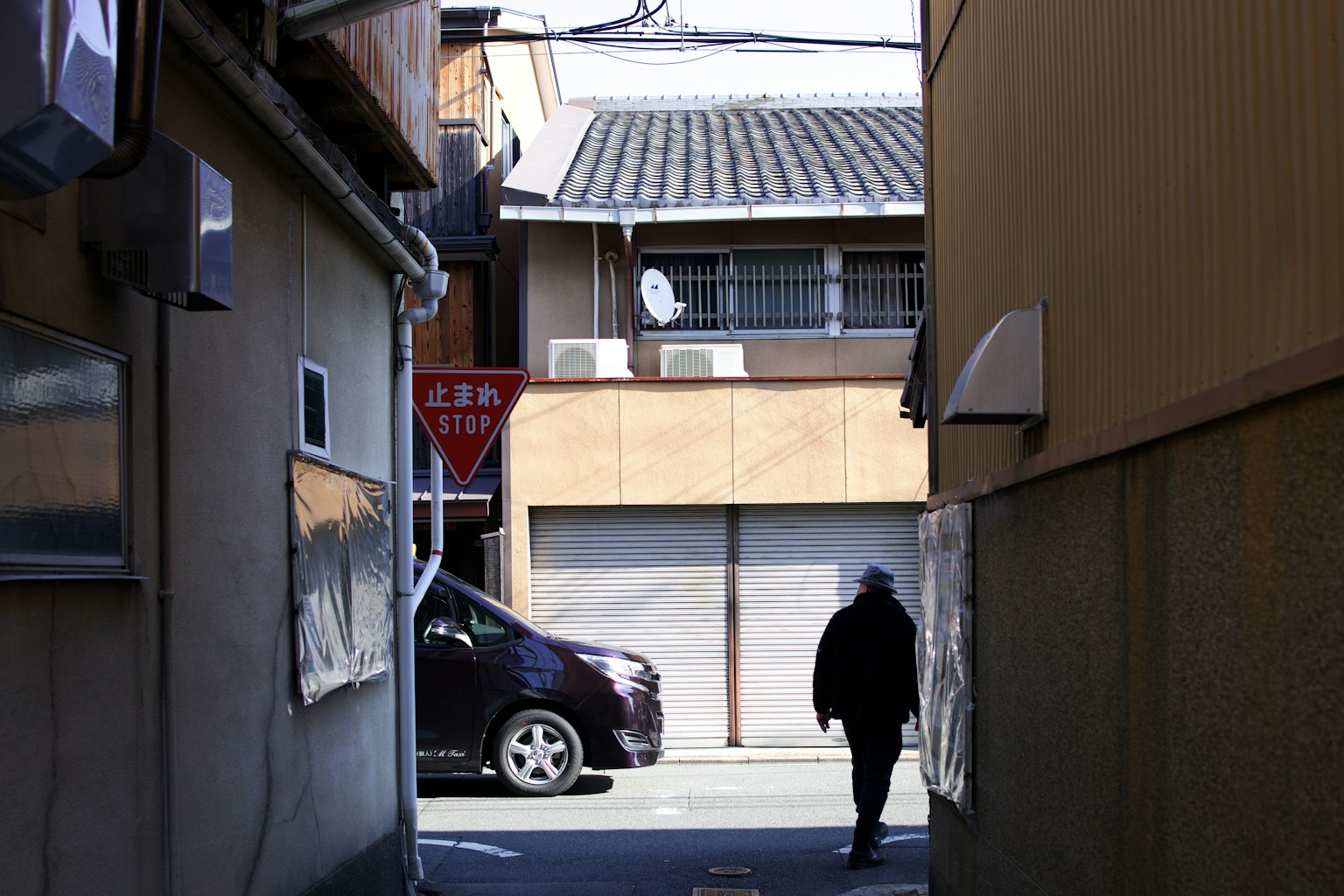 A person walking through a narrow alley with surrounding buildings