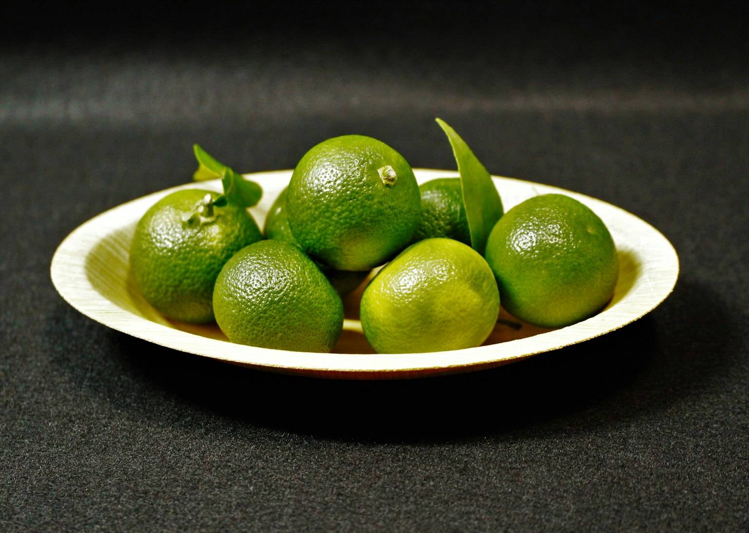 Fruits citrus verts disposés sur une assiette blanche