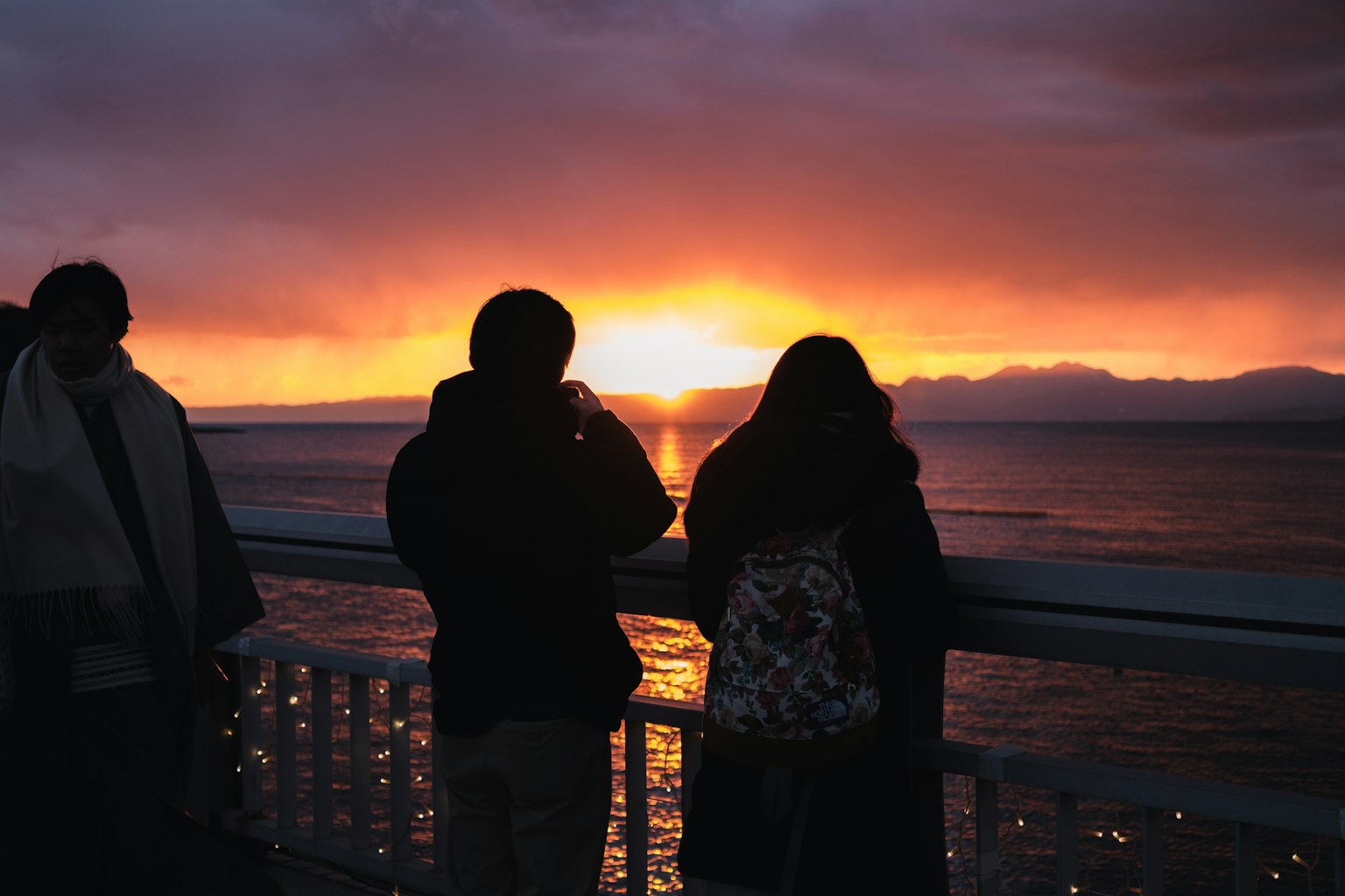 Des gens regardant le coucher de soleil sur l'océan