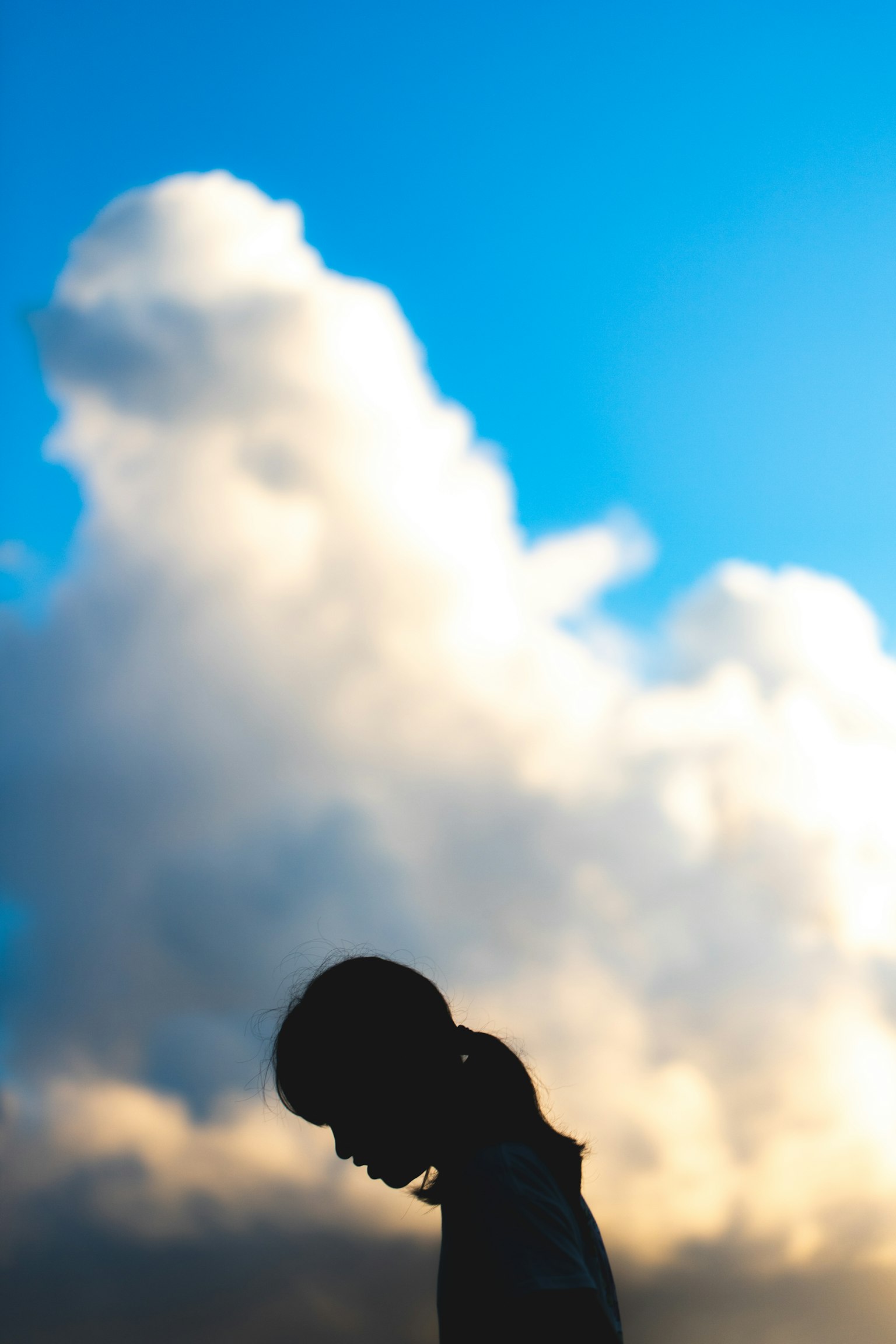 Silhouette di una donna contro un cielo blu e nuvole