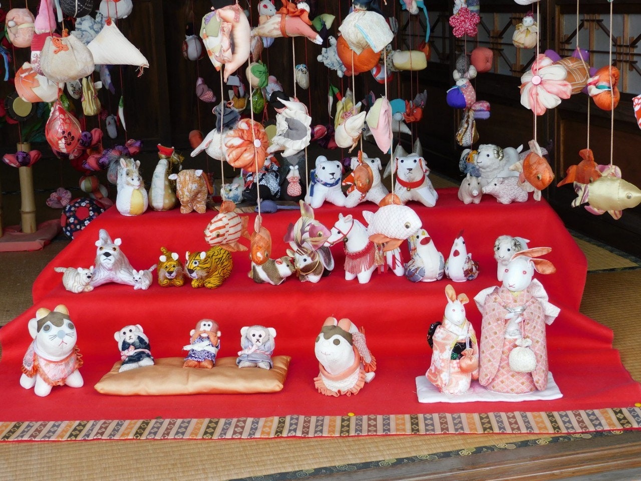 A display of plush toys and figurines arranged on a red cloth