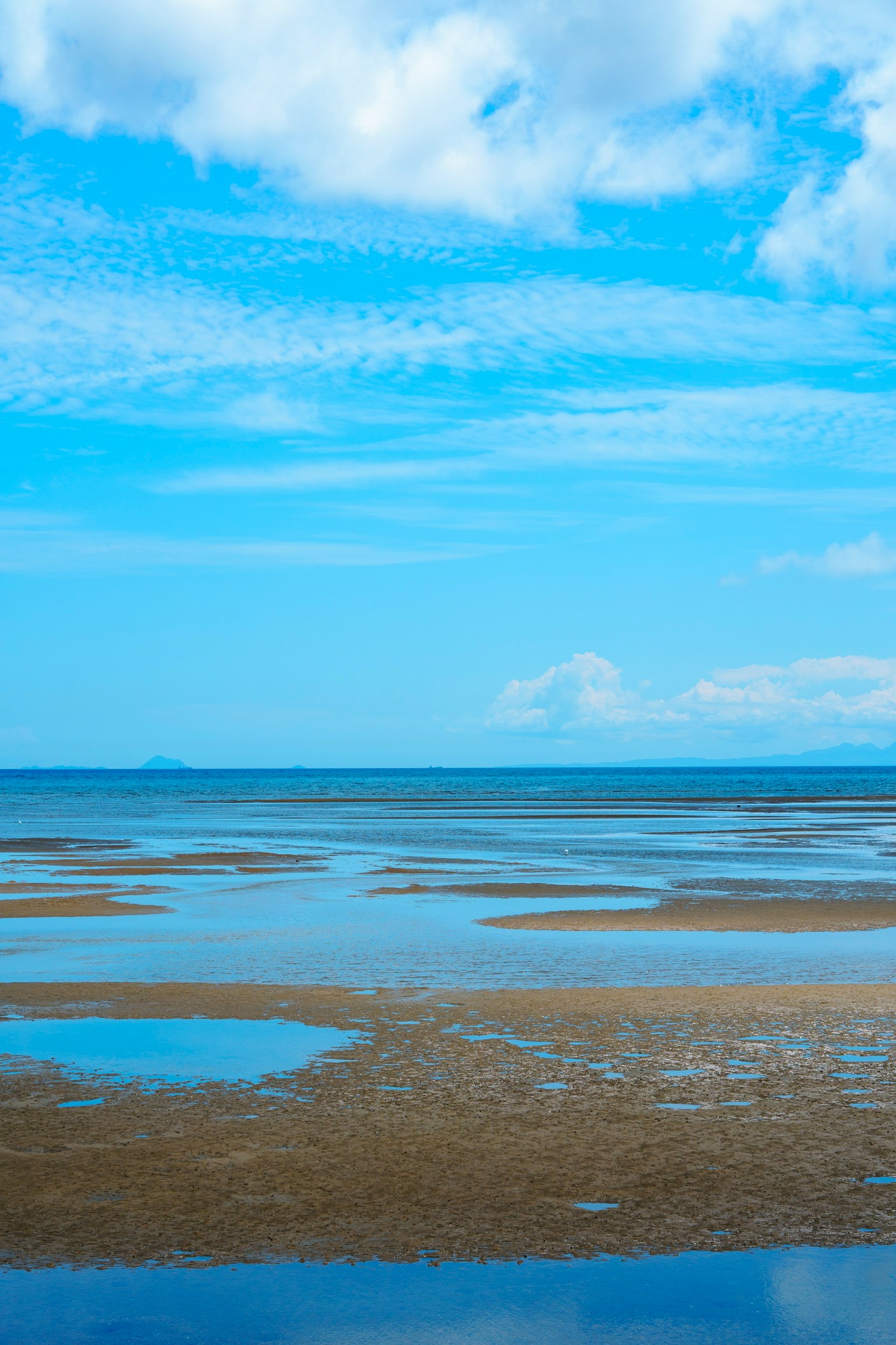 Lahan pasang yang luas dengan langit biru dan laut tenang