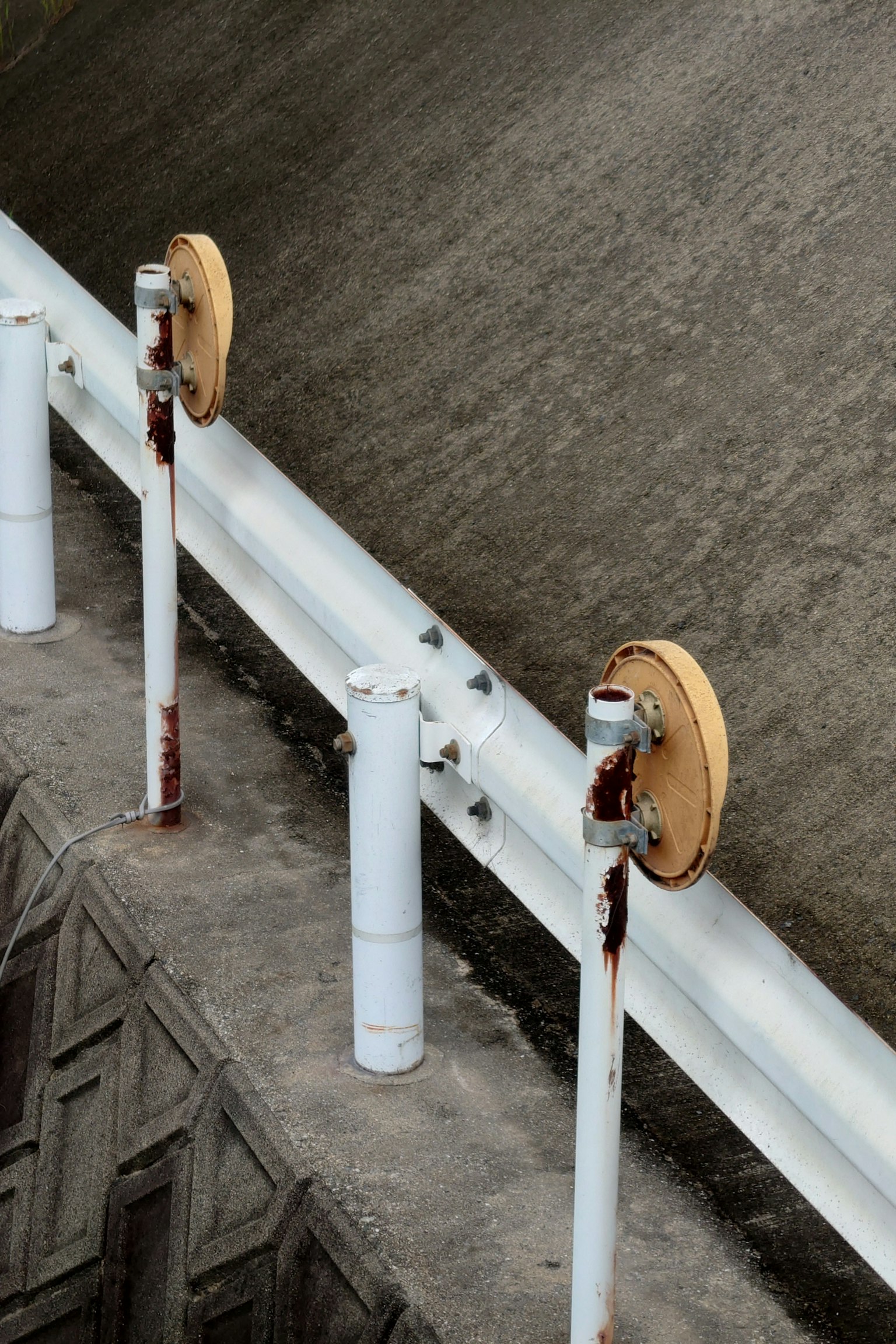 Close-up of a dam top featuring white pipes and wooden wheels