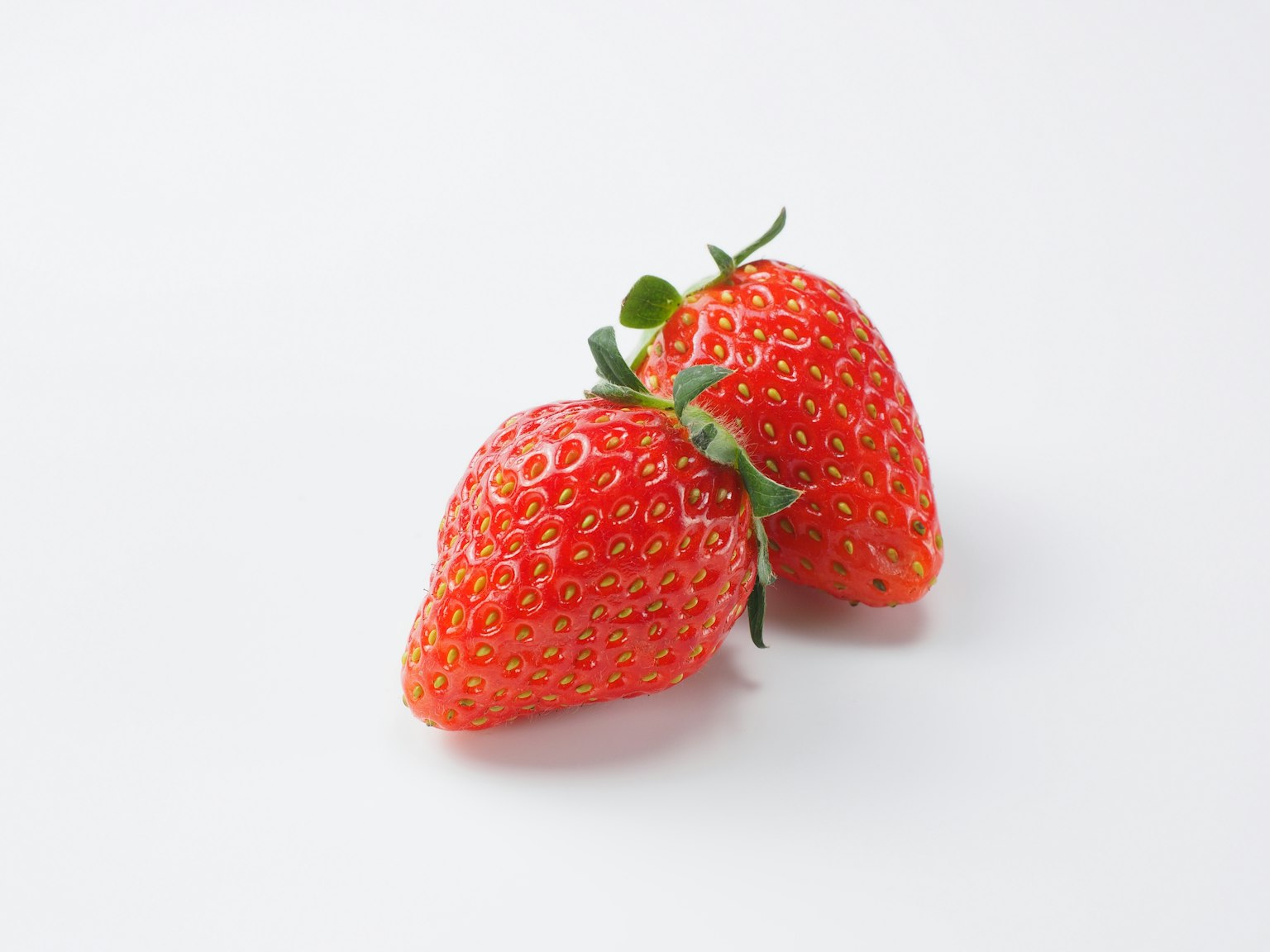 Two fresh strawberries on a white background