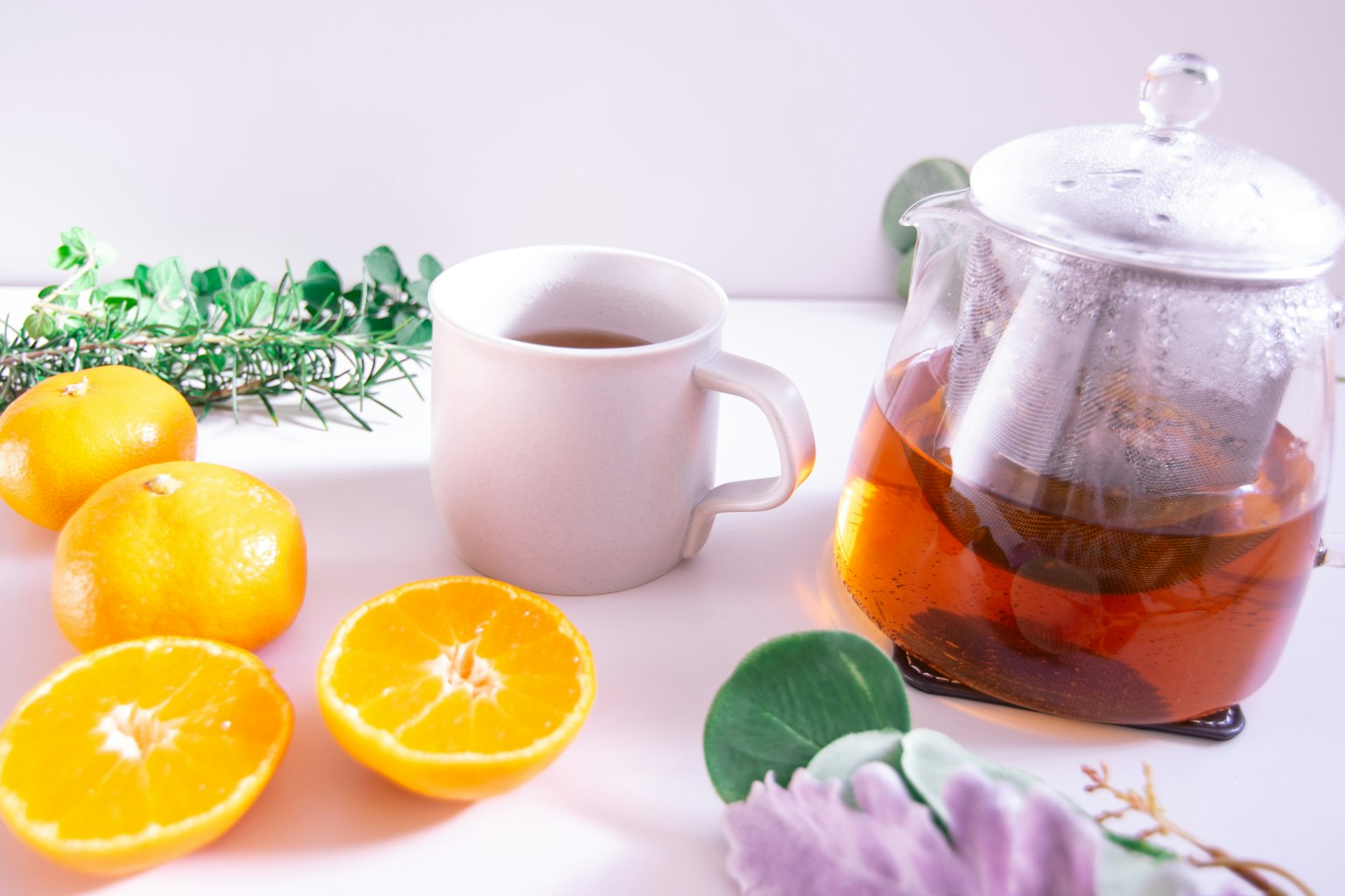 Image of tea in a glass pot with oranges and a white cup