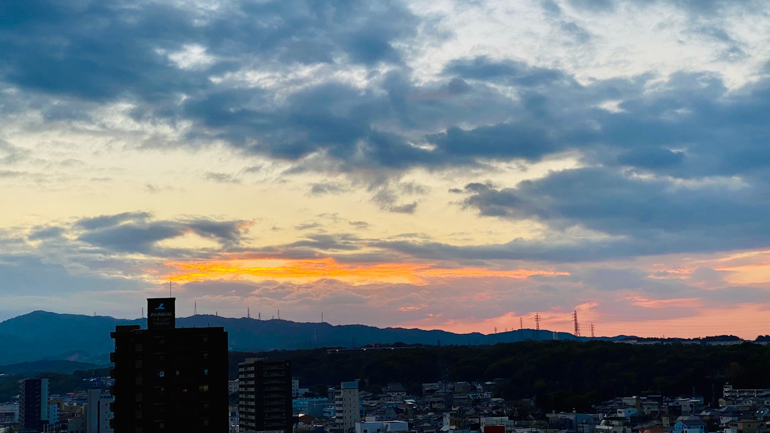 Stadtlandschaft mit Sonnenuntergangshimmel und Bergen im Hintergrund