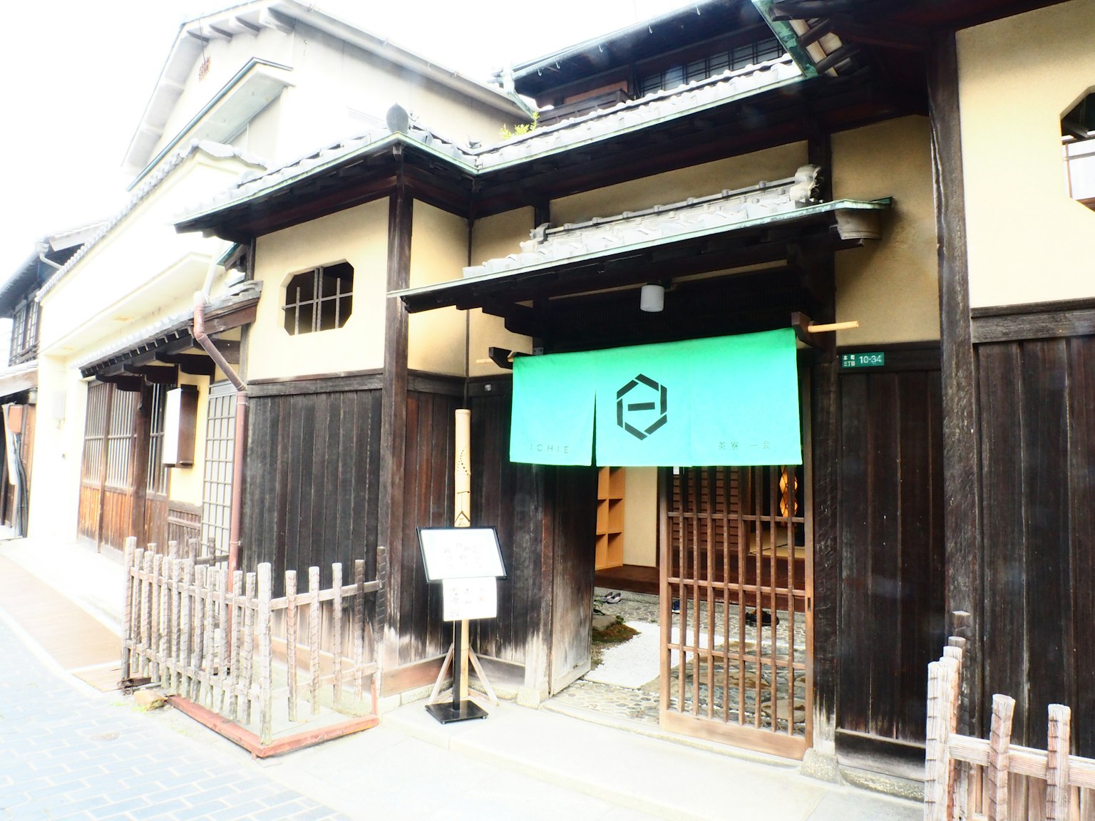 Traditional Japanese house exterior with a green noren curtain wooden fence in front