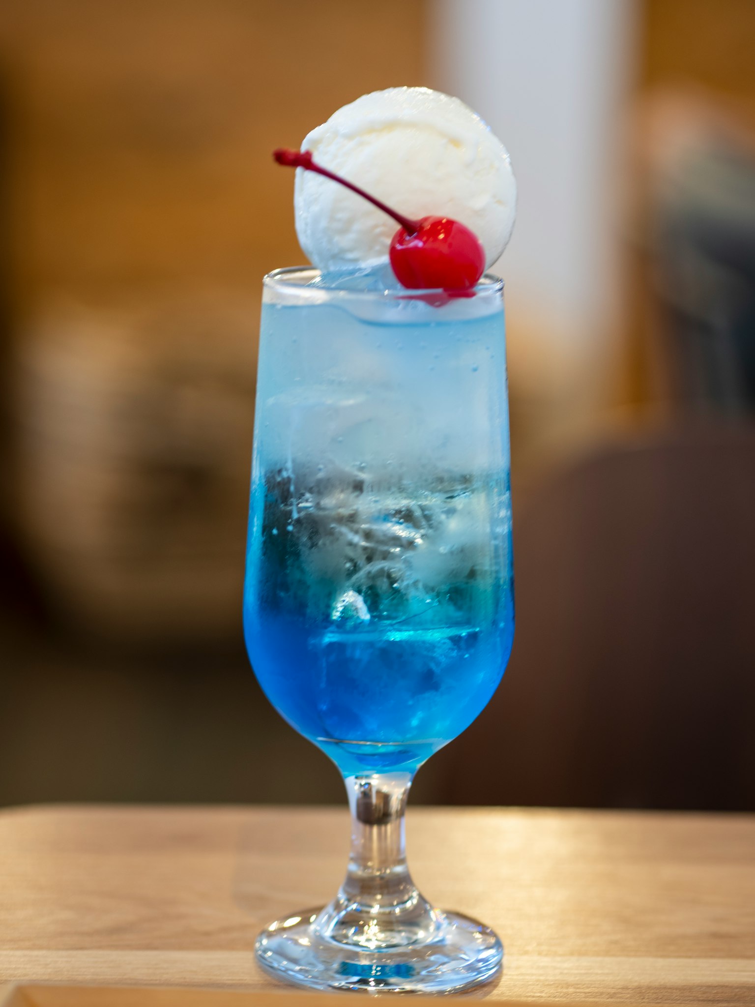 Un cóctel azul cubierto con helado y una cereza