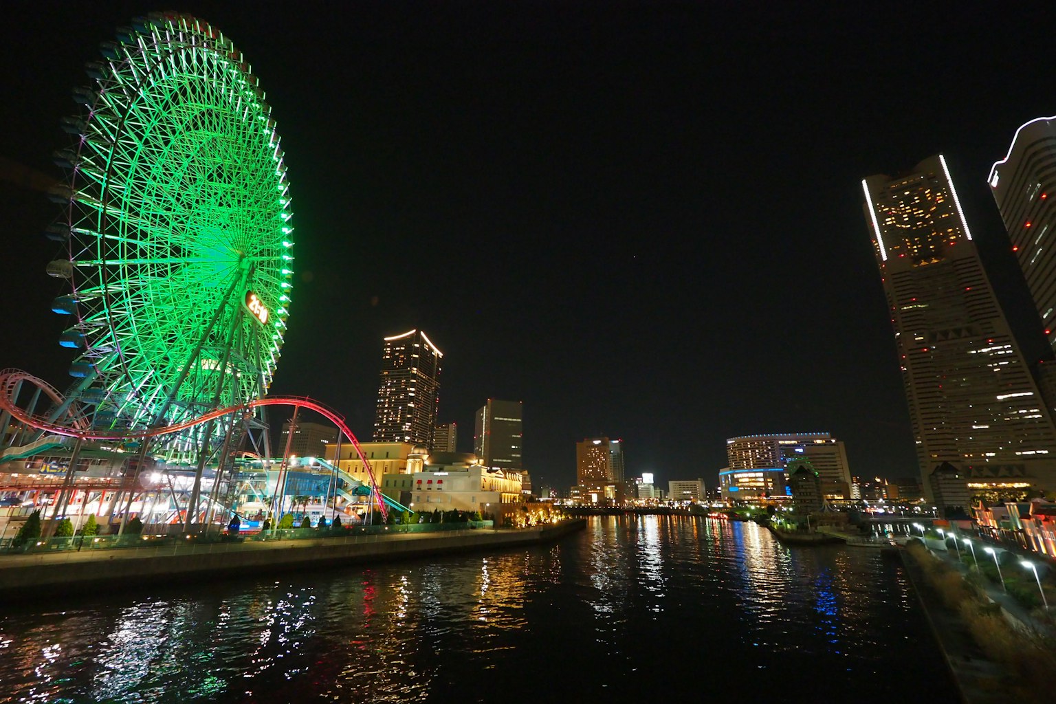Nachtsicht des grünen Riesenrads und der Stadtlandschaft am Wasser in Yokohama