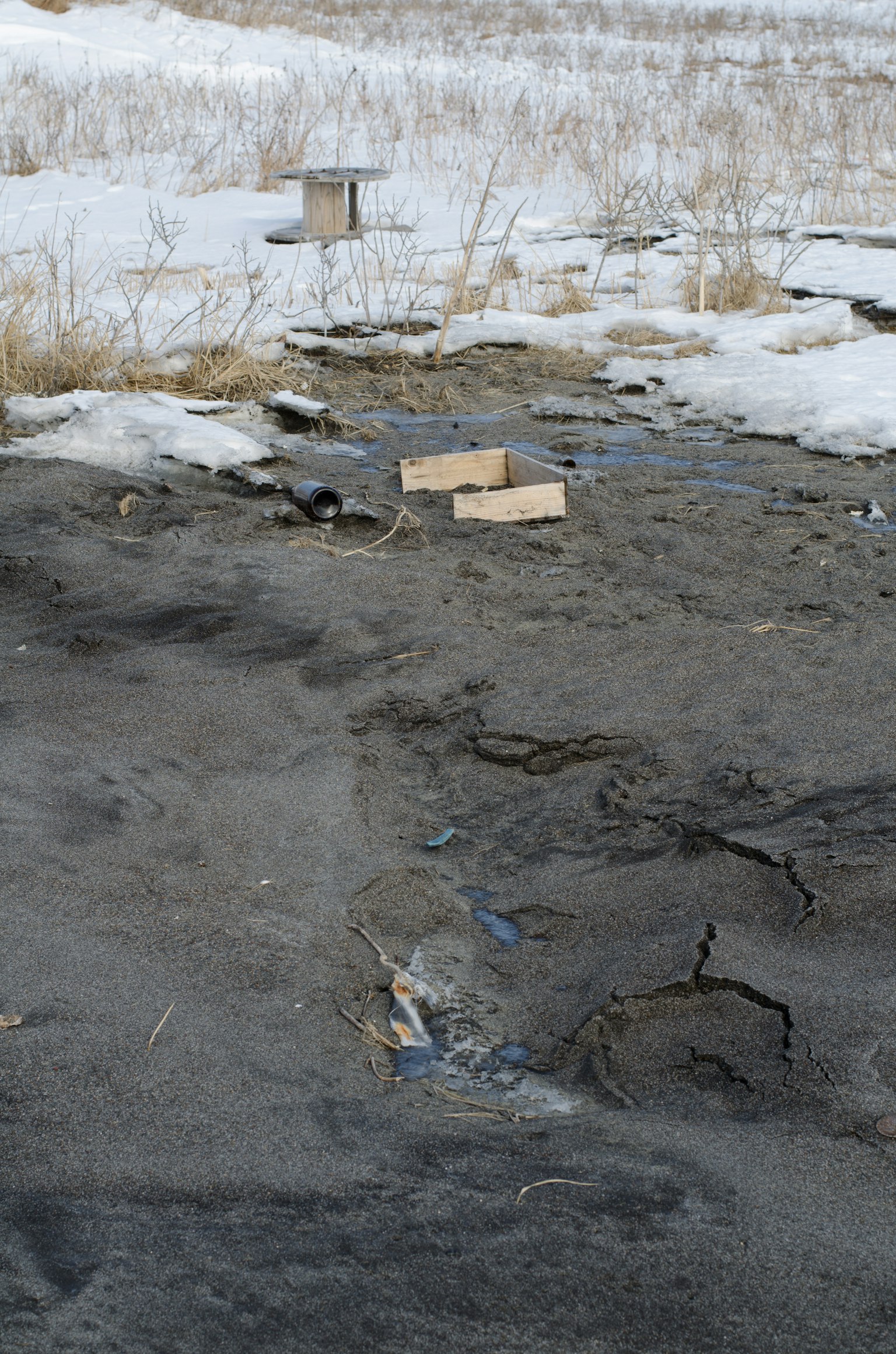 Zwei Holzplatten auf einem öden Boden mit Schnee und Gras