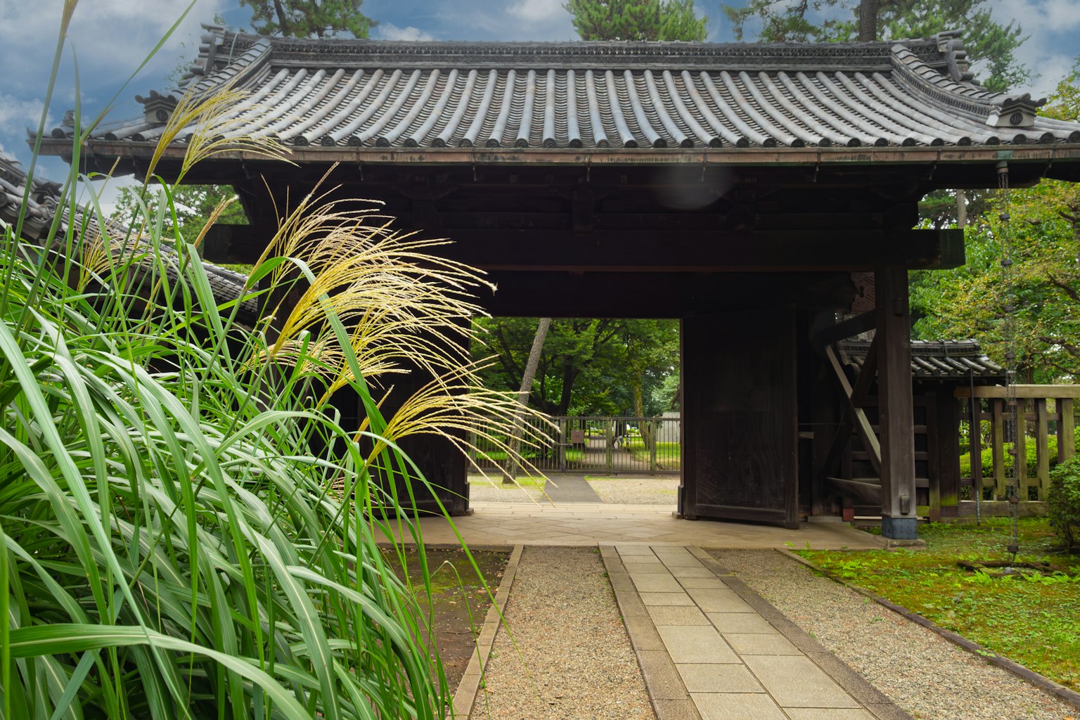 Traditionelles japanisches Tor umgeben von üppigem Grün und dekorativem Gras