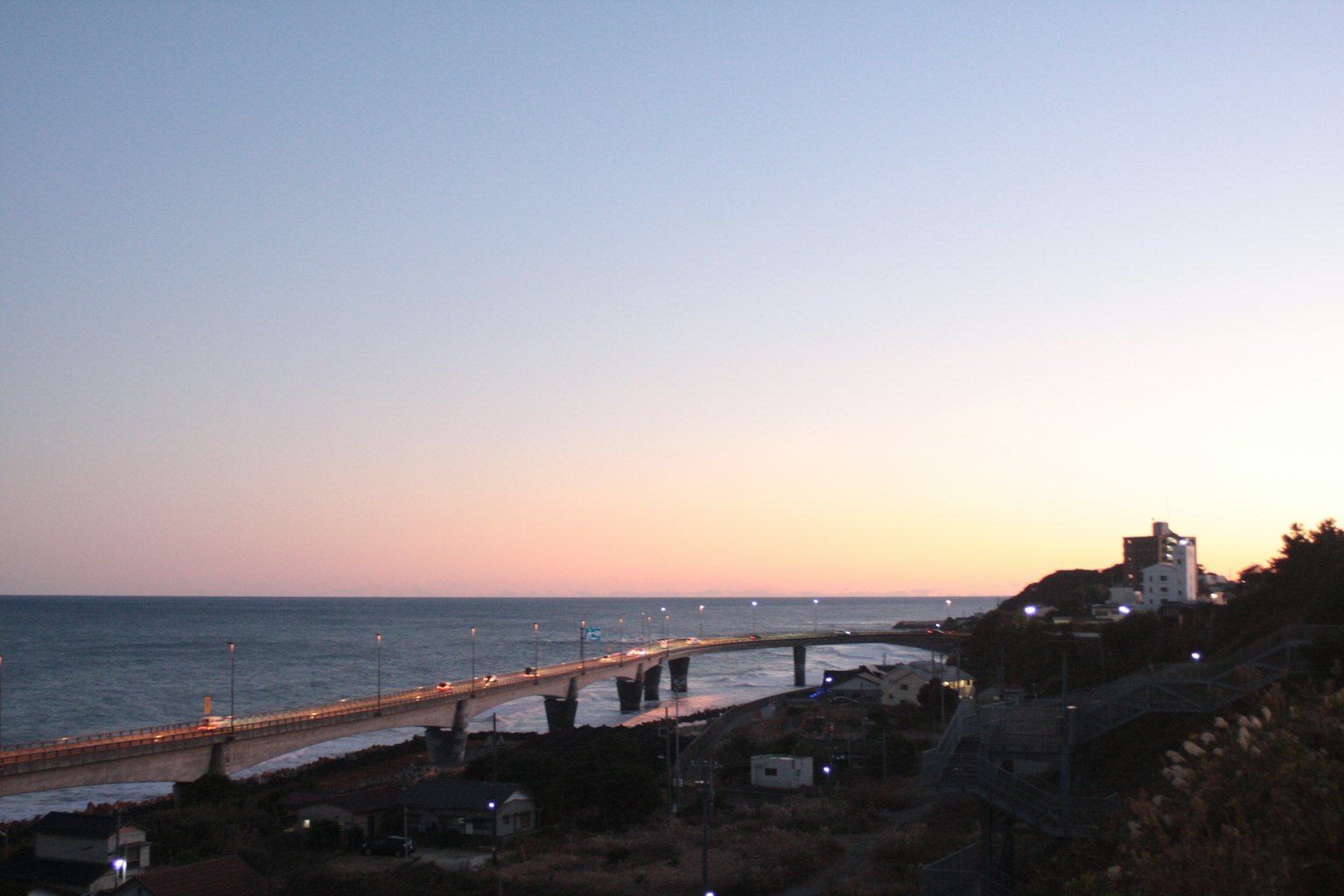 Coastal view at dusk with a bridge and shoreline