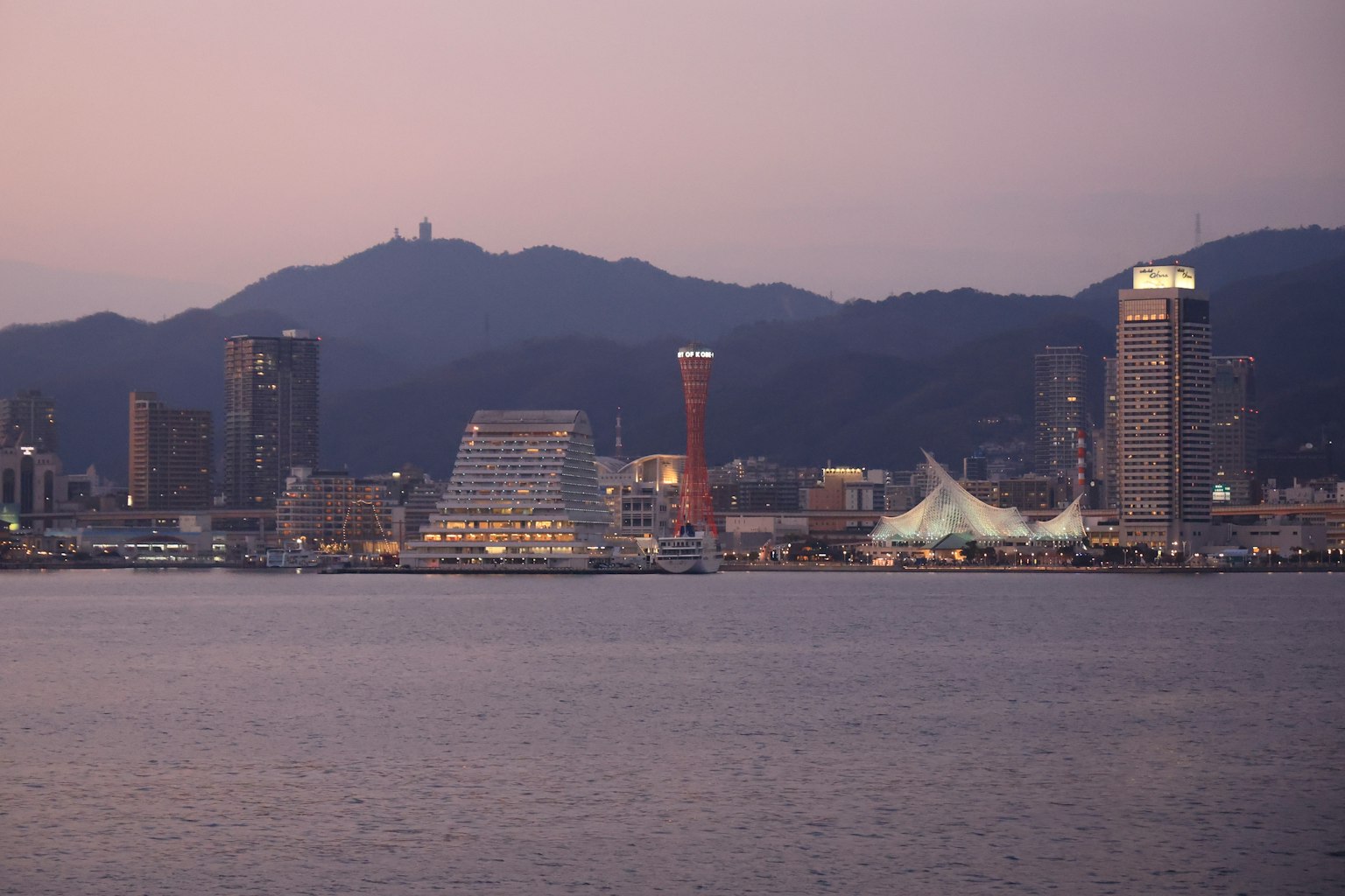 Vue nocturne de la ville de Kobe avec des gratte-ciels et des montagnes au-delà de la mer