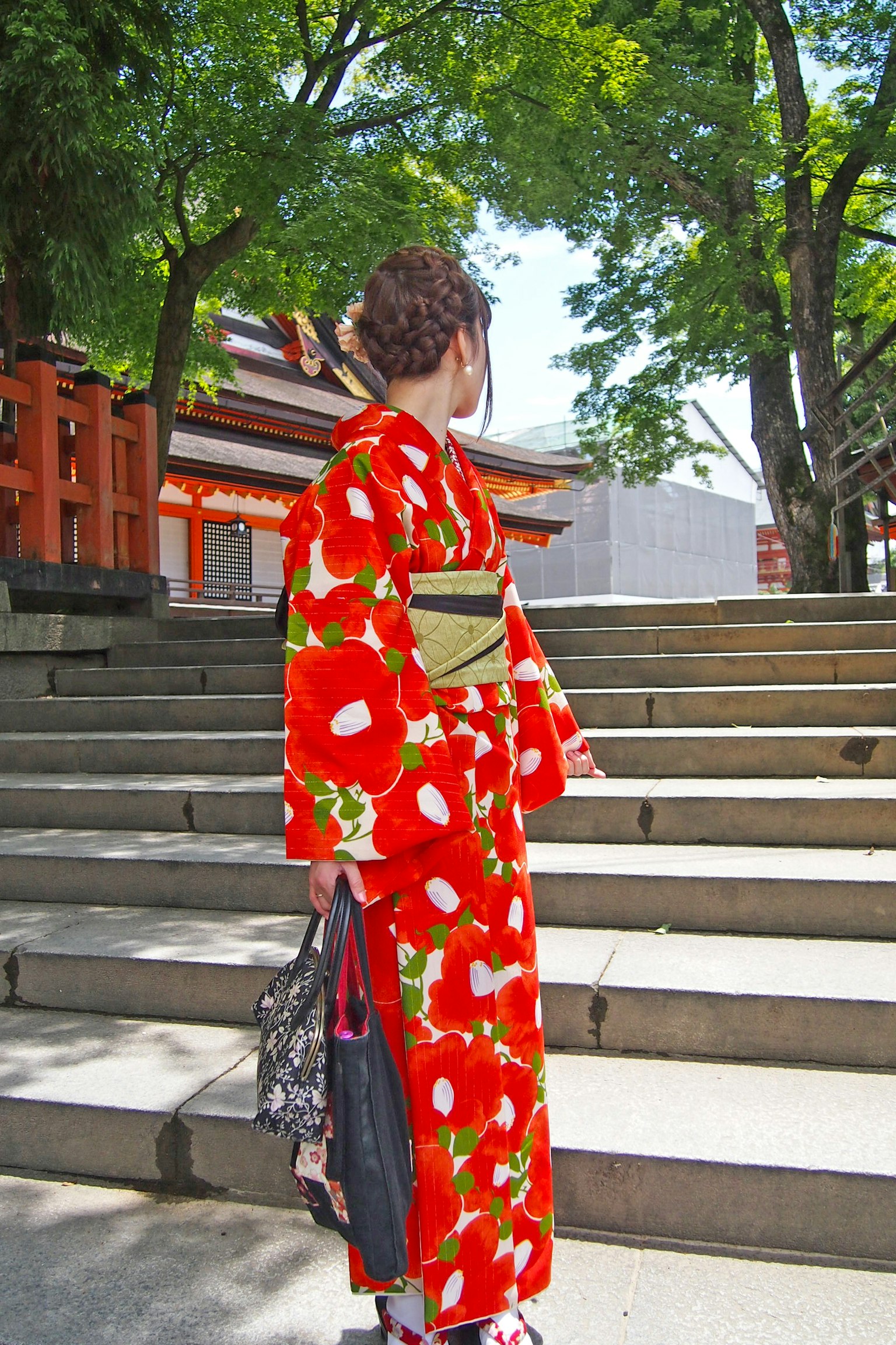 Frau in einem roten Blumen-Kimono, die eine Treppe hinaufgeht
