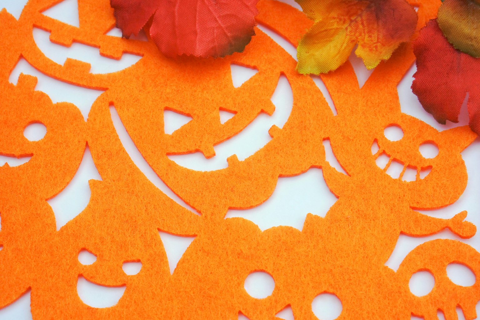 Orange felt Halloween decorations with smiling and spooky faces and flower petals
