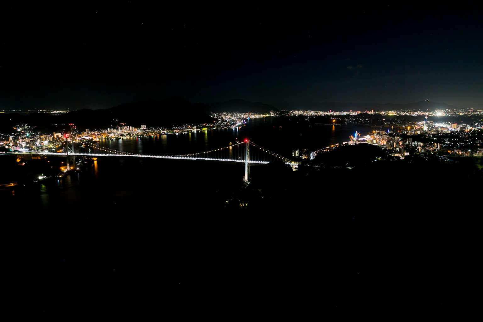 Puente iluminado y luces de la ciudad de noche