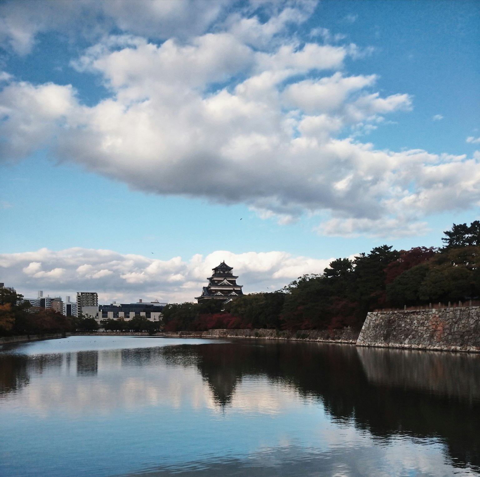 Paesaggio con un castello riflesso nell'acqua sotto un cielo blu con nuvole