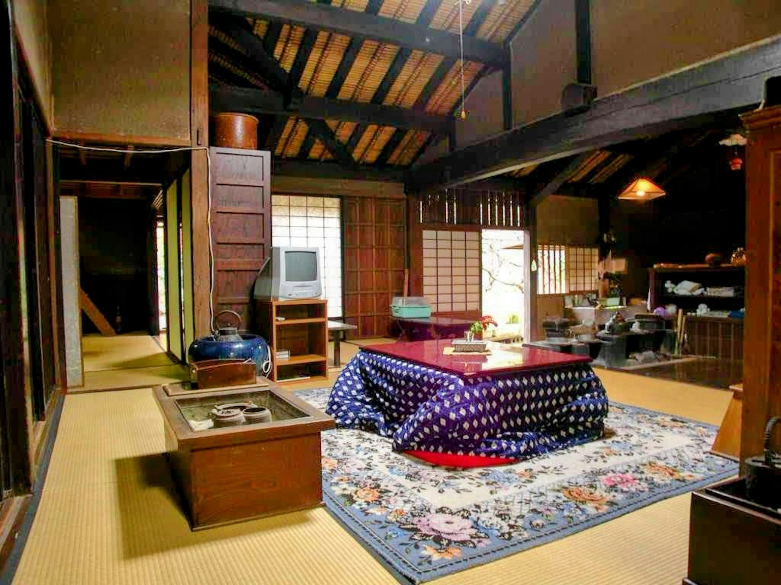 传统日本房屋内部，榻榻米地板，木梁，红色桌布的火锅桌和日本装饰