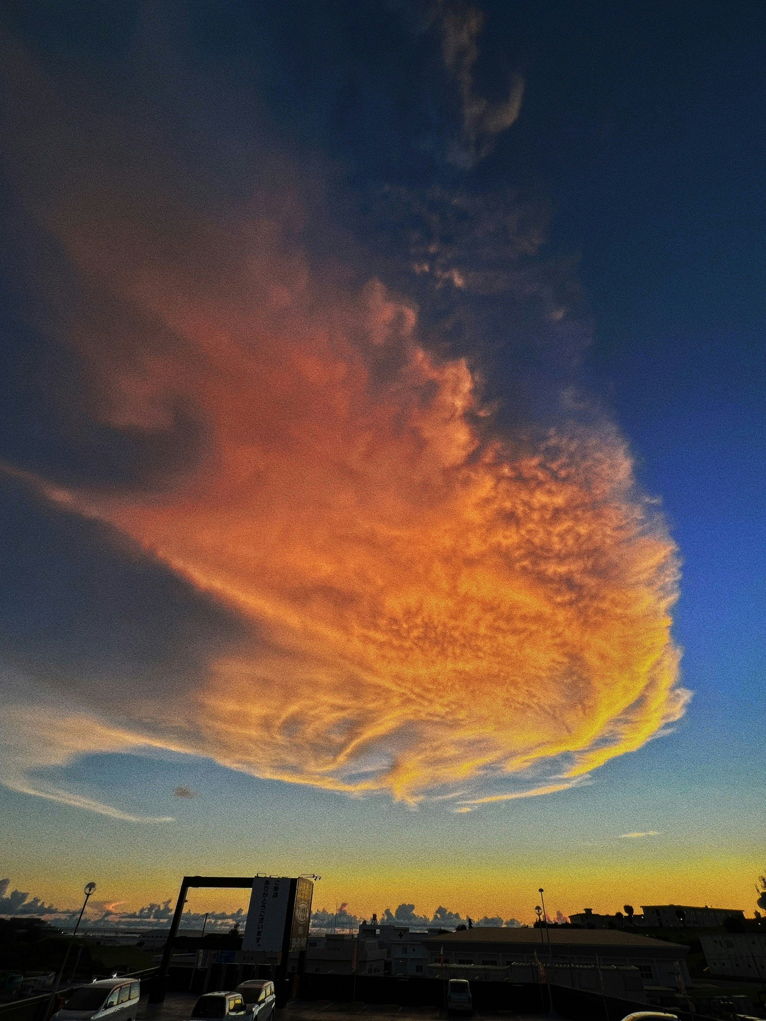 Awan oranye yang indah membentang di langit biru saat matahari terbenam