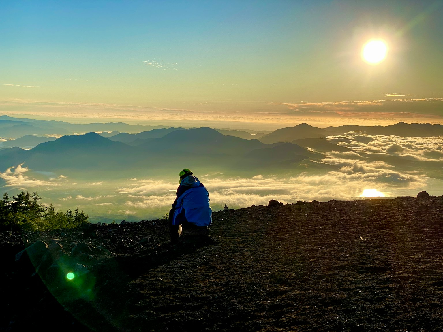 Senderista sentado en un mirador de montaña con amanecer y nubes