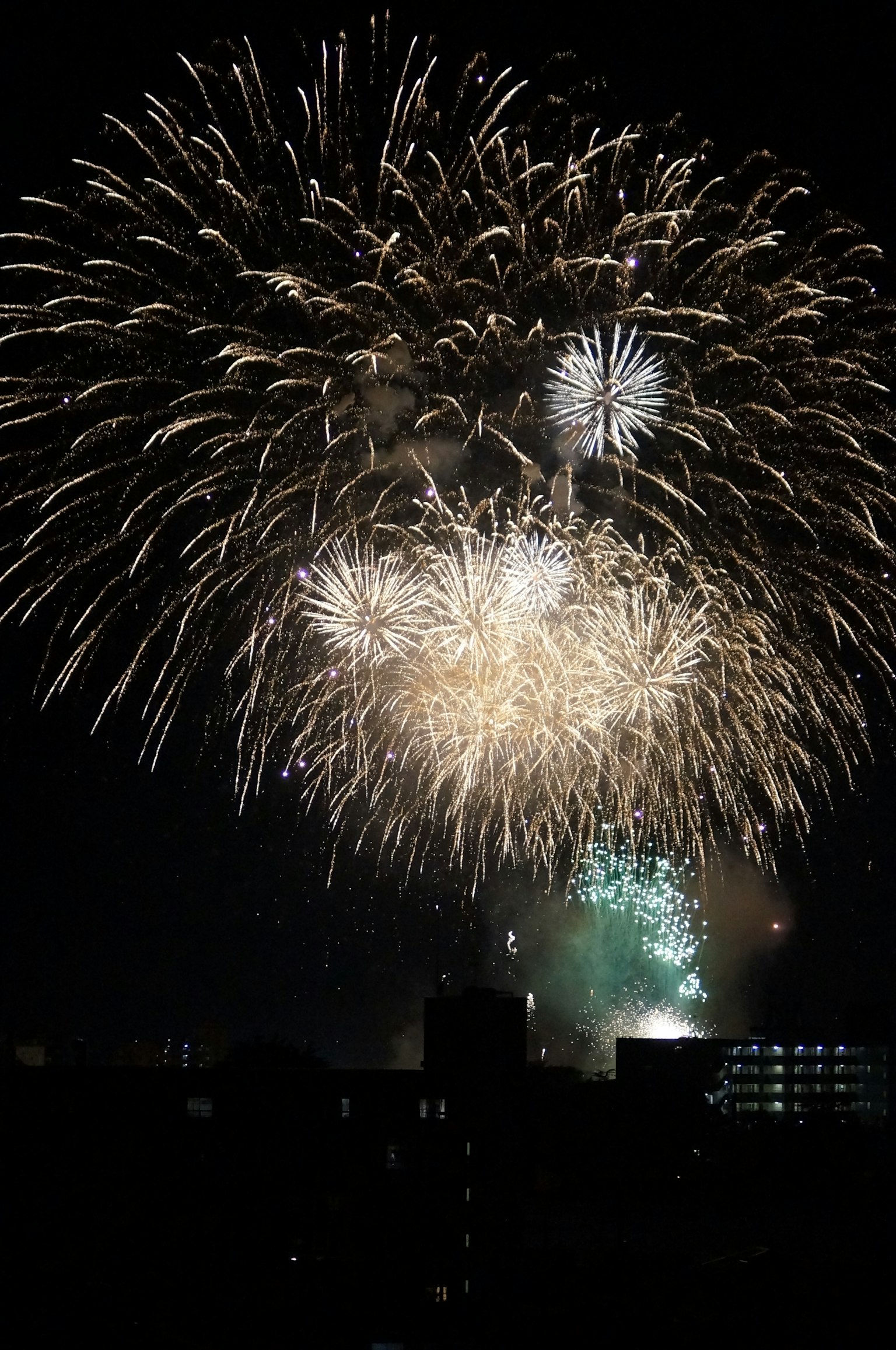 夜空中绚丽的烟花表演，闪烁的金色和绿色火花