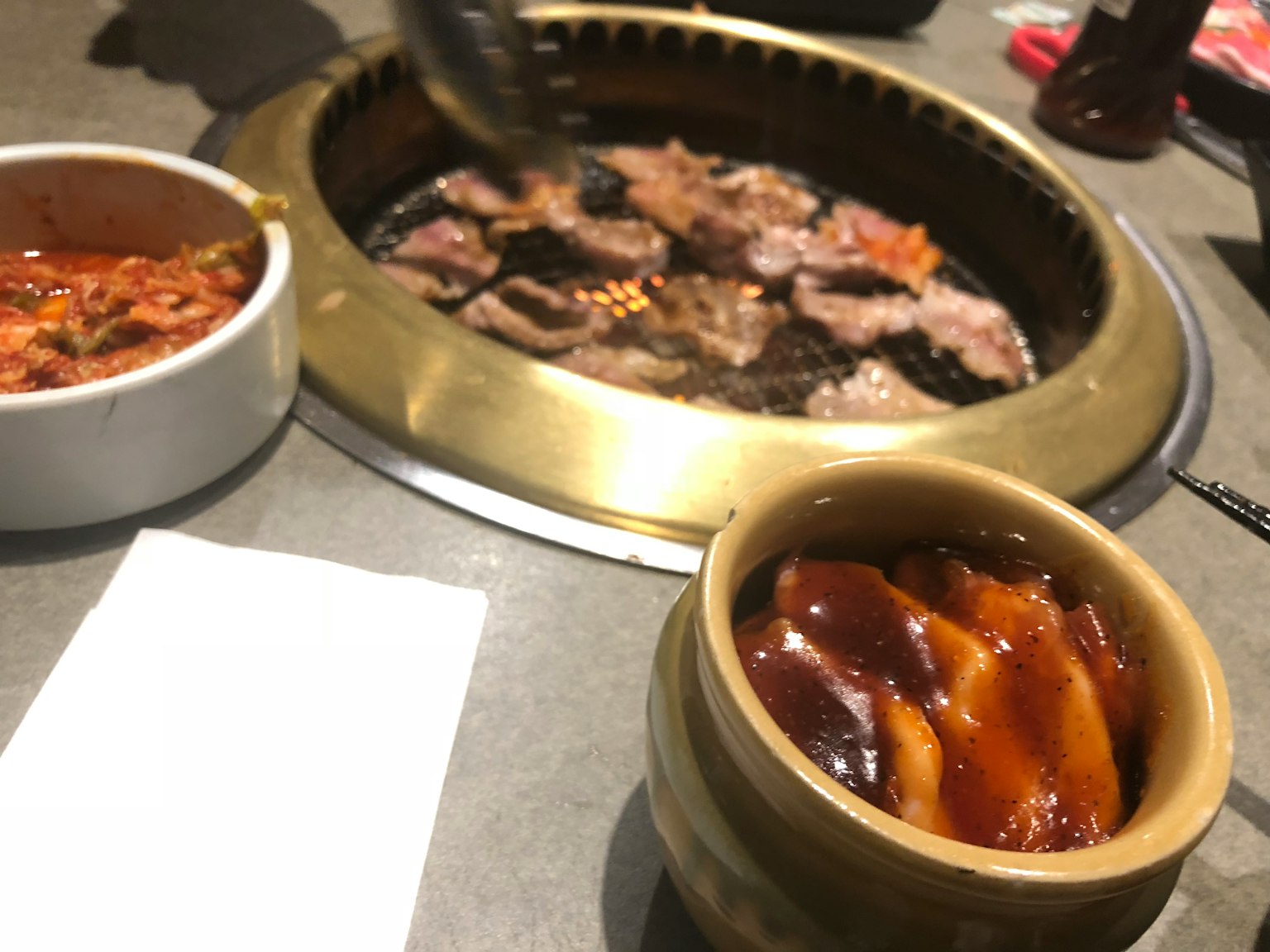 桌子上有燒烤肉和配菜如泡菜和醬汁