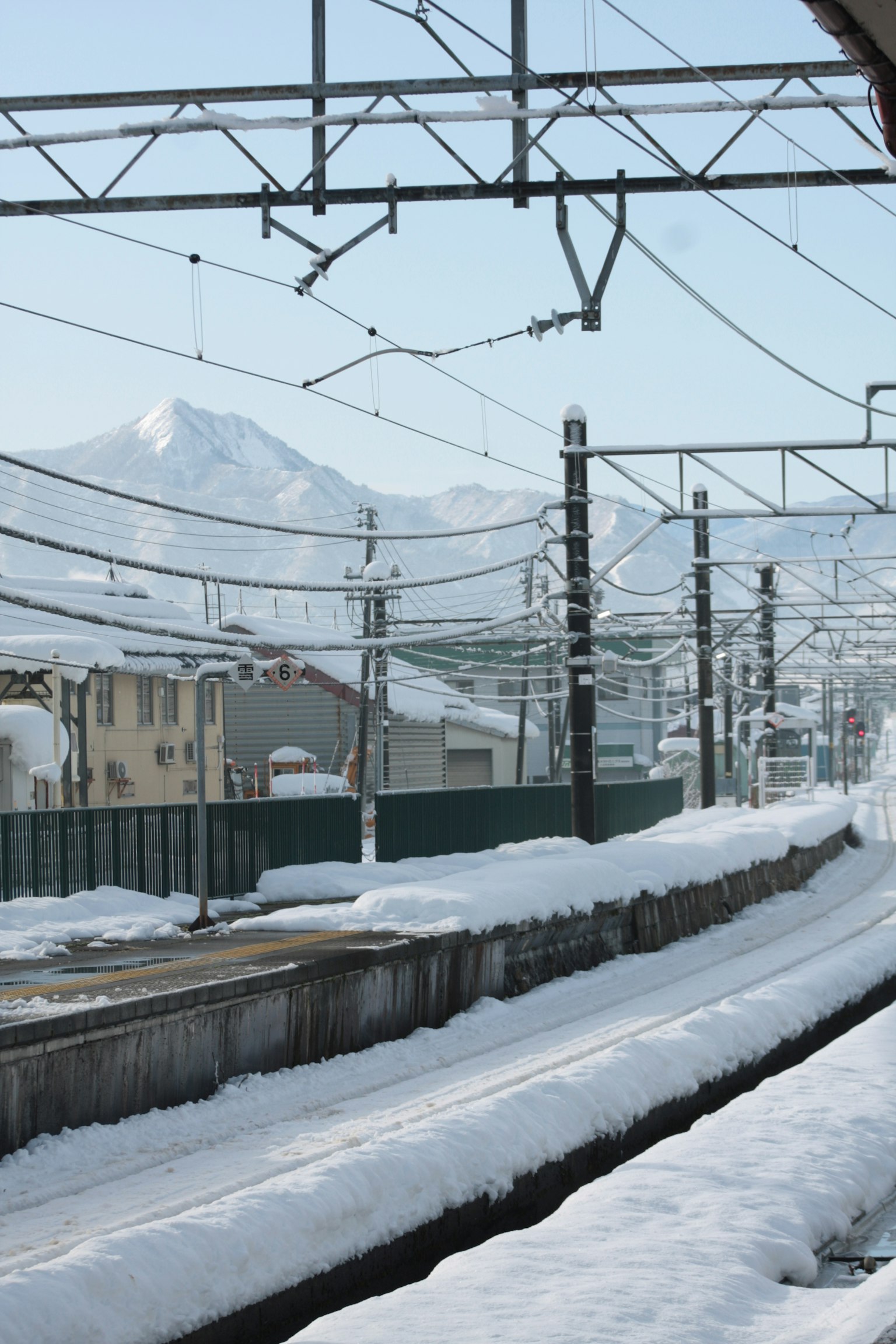 Vías de tren cubiertas de nieve con montañas al fondo