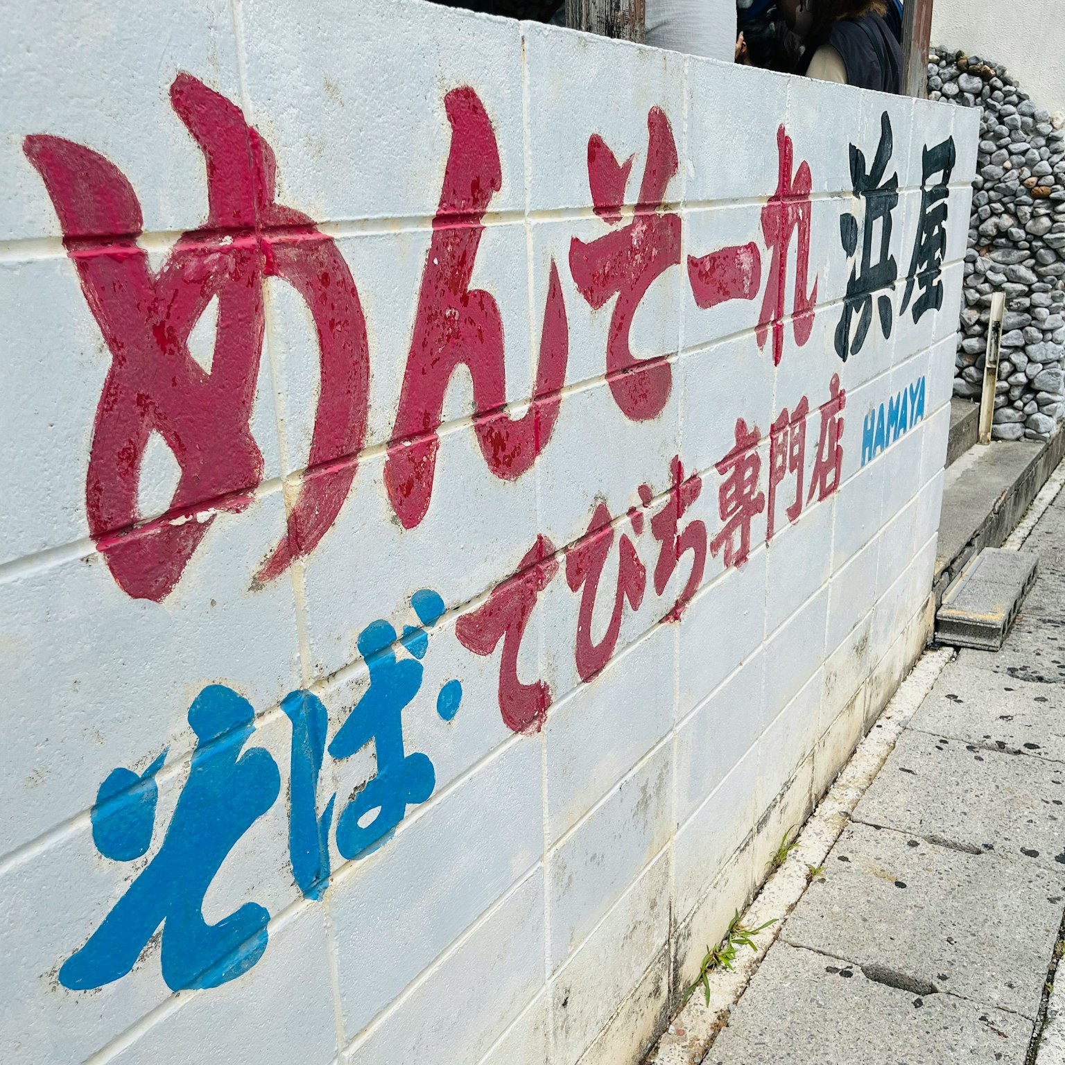 一面白色墙壁上用红色和蓝色文字显示商店名称和菜单