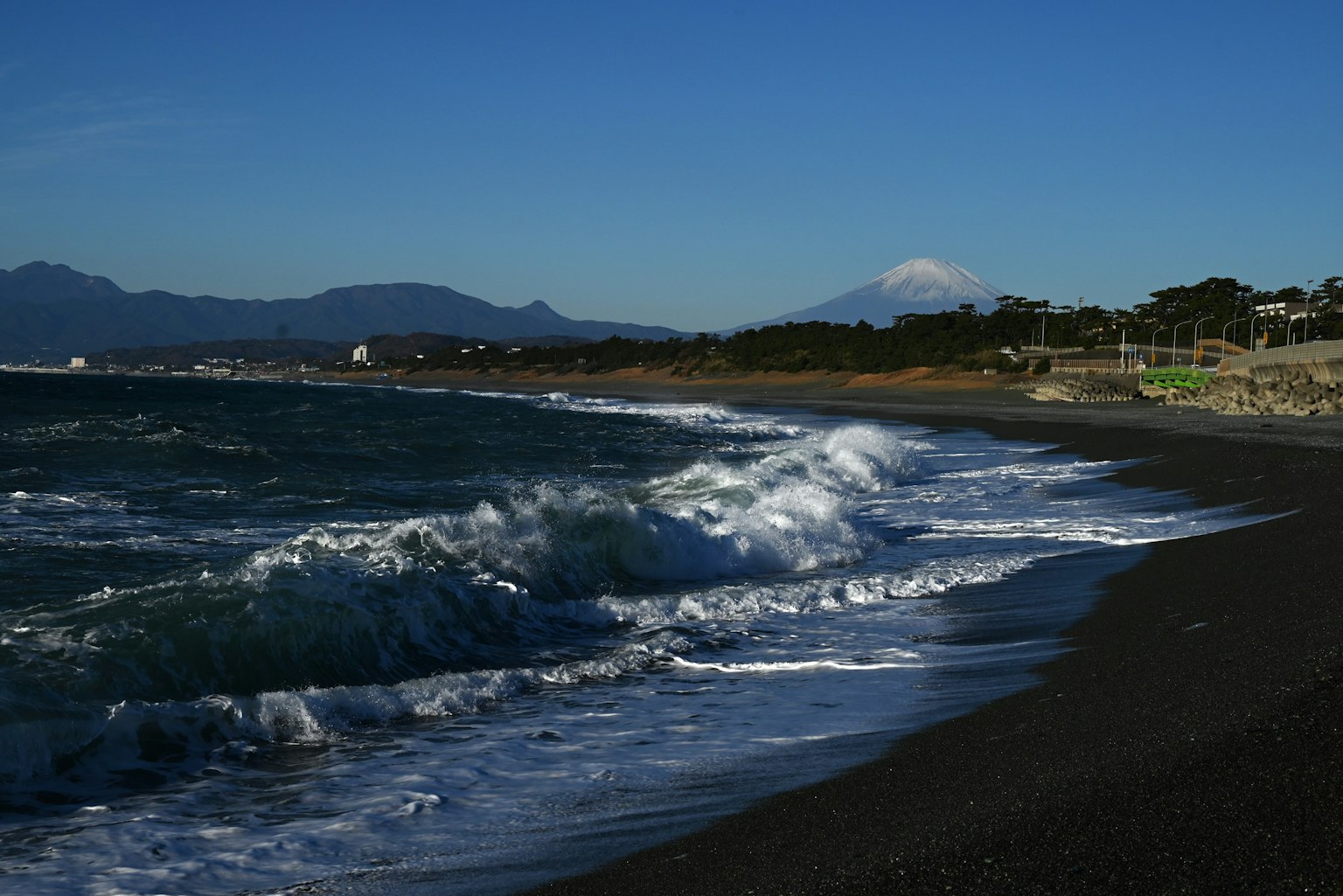Panoramablick auf blaue Ozeanwellen, die an einen schwarzen Sandstrand schlagen