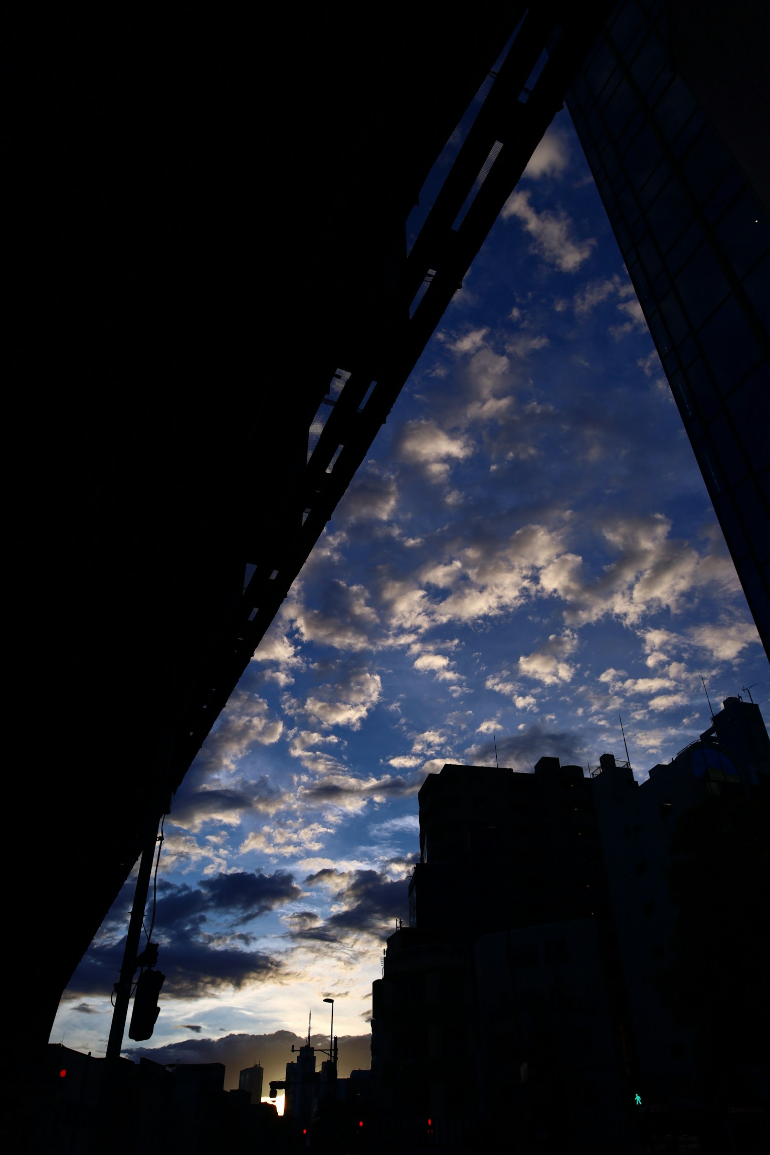 Silhouette of buildings against a sunset sky with clouds