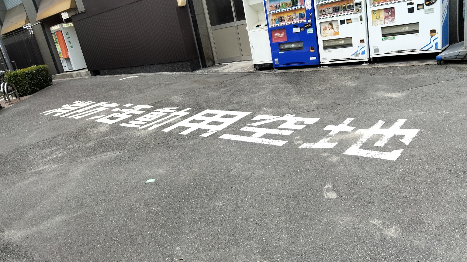 Terreno con caratteri bianchi che indicano uno spazio di parcheggio circondato da distributori automatici