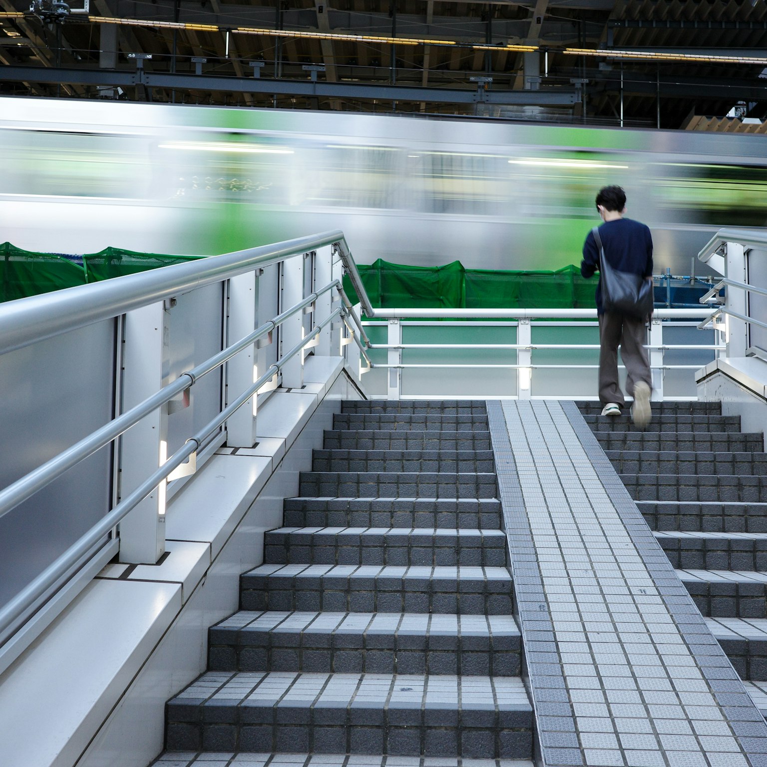 階段を上る男性と流れる電車の背景