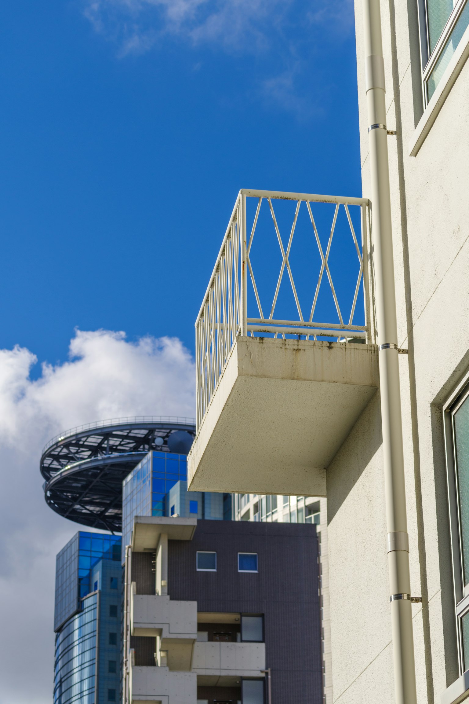 Balcone bianco sotto un cielo blu con edifici moderni