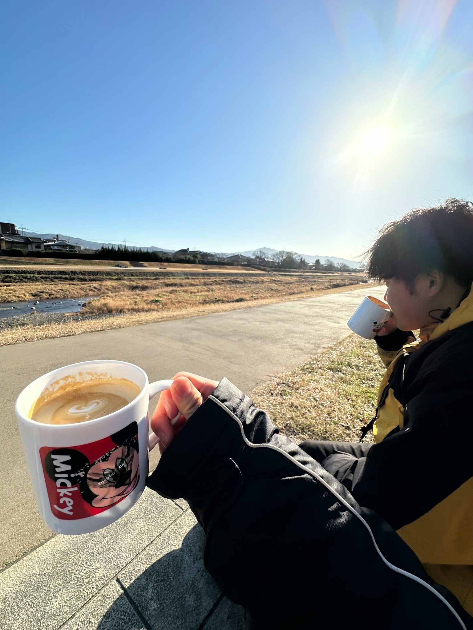 晴れた日、コーヒーを飲む若い男性、背景に自然風景が広がる