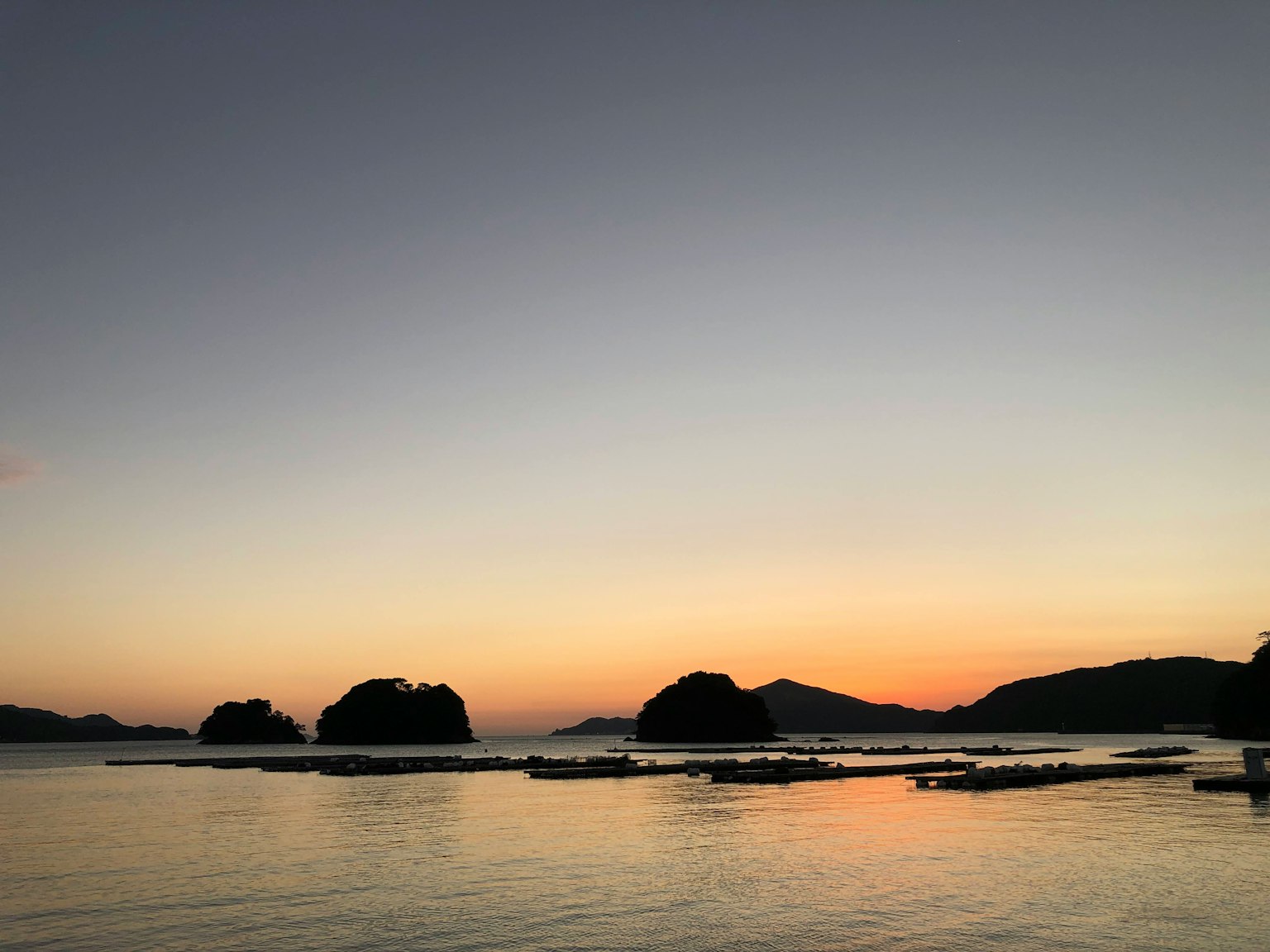 Vista panoramica di un tramonto su acque calme con isole in lontananza