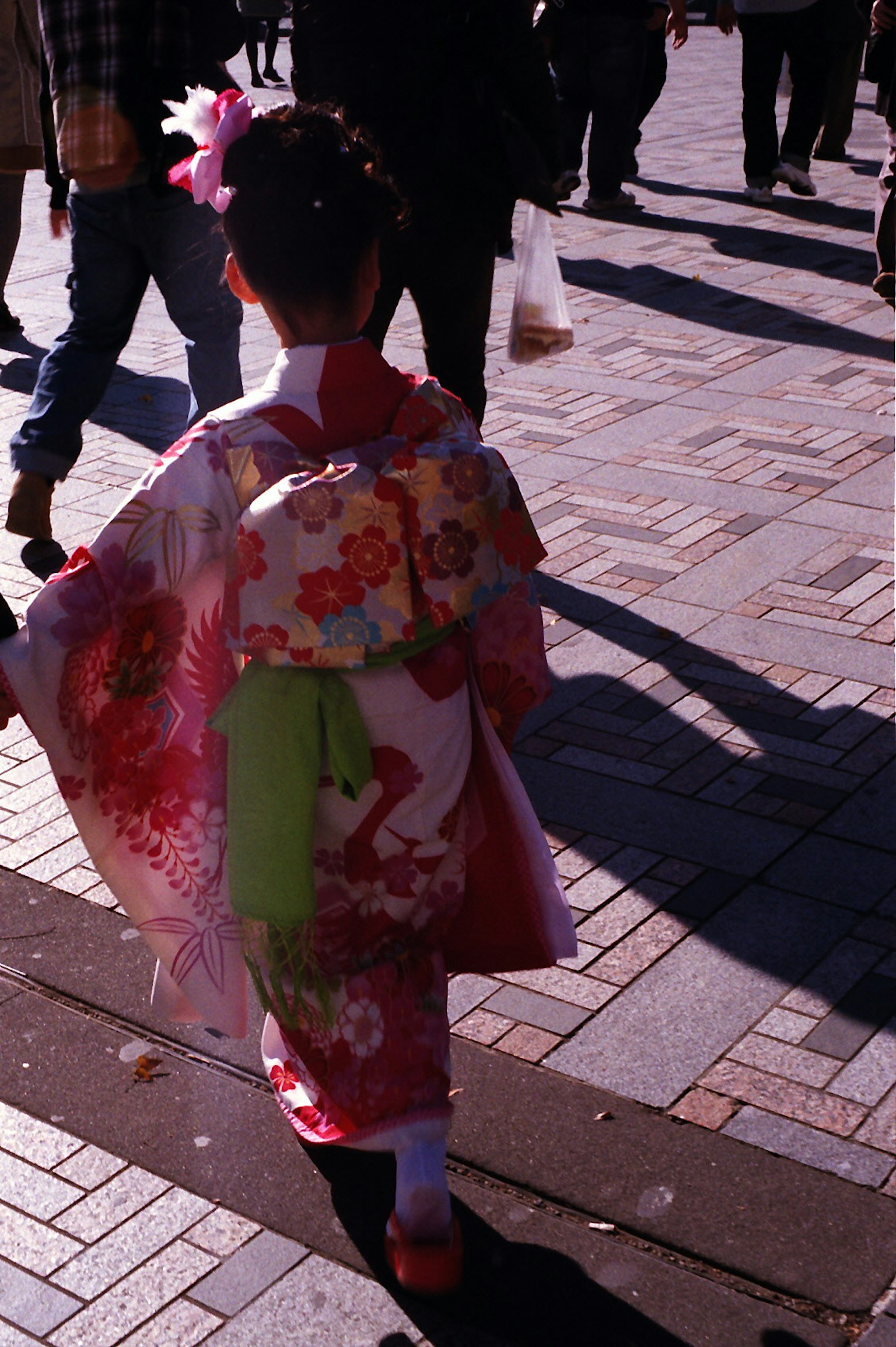 Un bambino in kimono rosso che cammina in una strada affollata