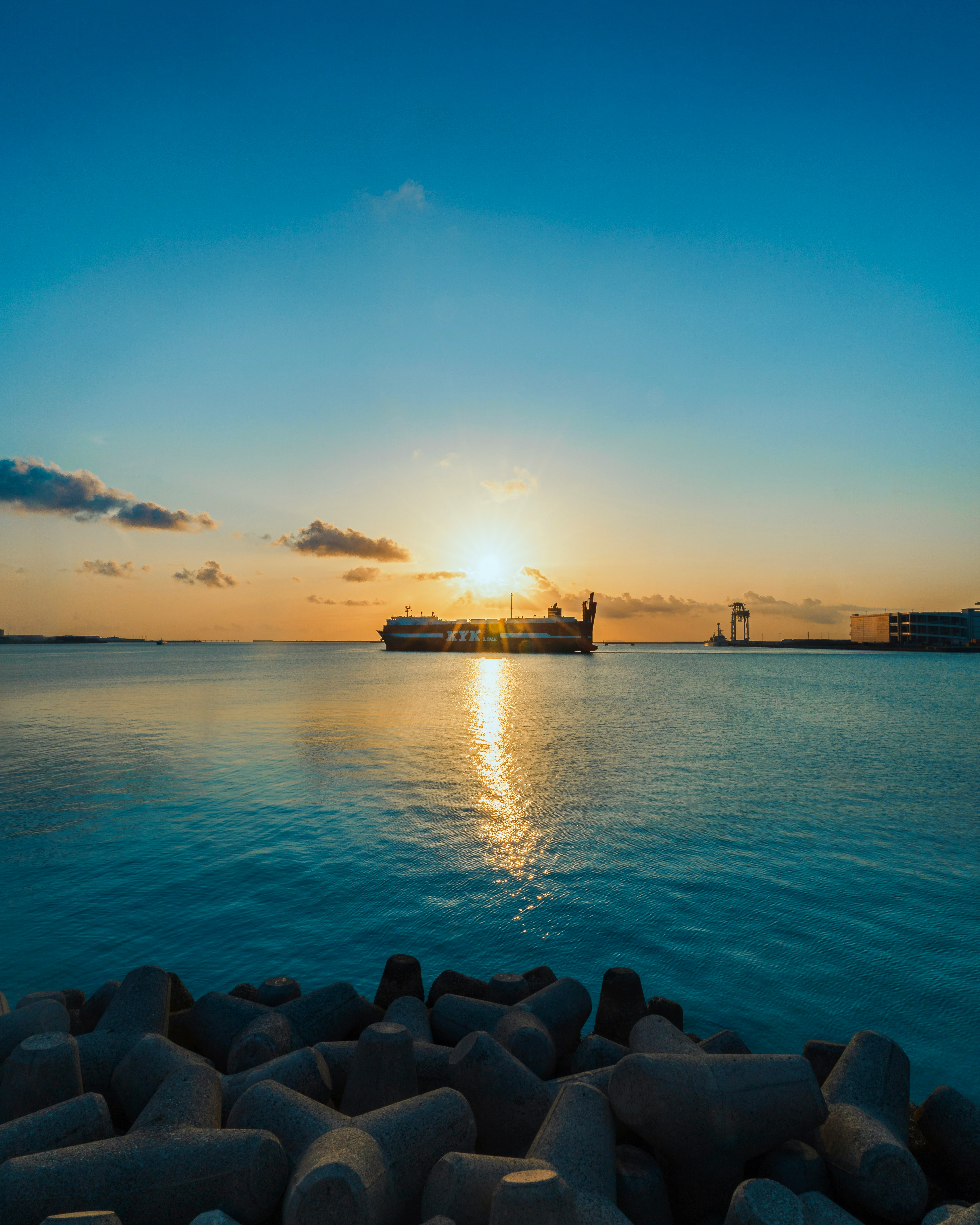 sunset-lit seaside breakwater with a ship