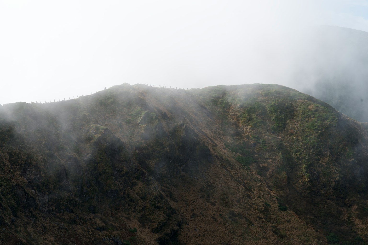 Paysage montagneux enveloppé de brume avec pentes verdoyantes