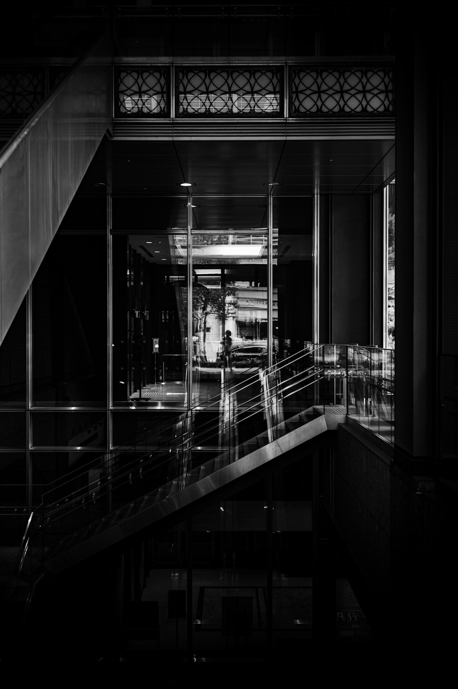 Schwarz-Weiß-Foto eines Innenraums mit Glasgeländern und Treppen