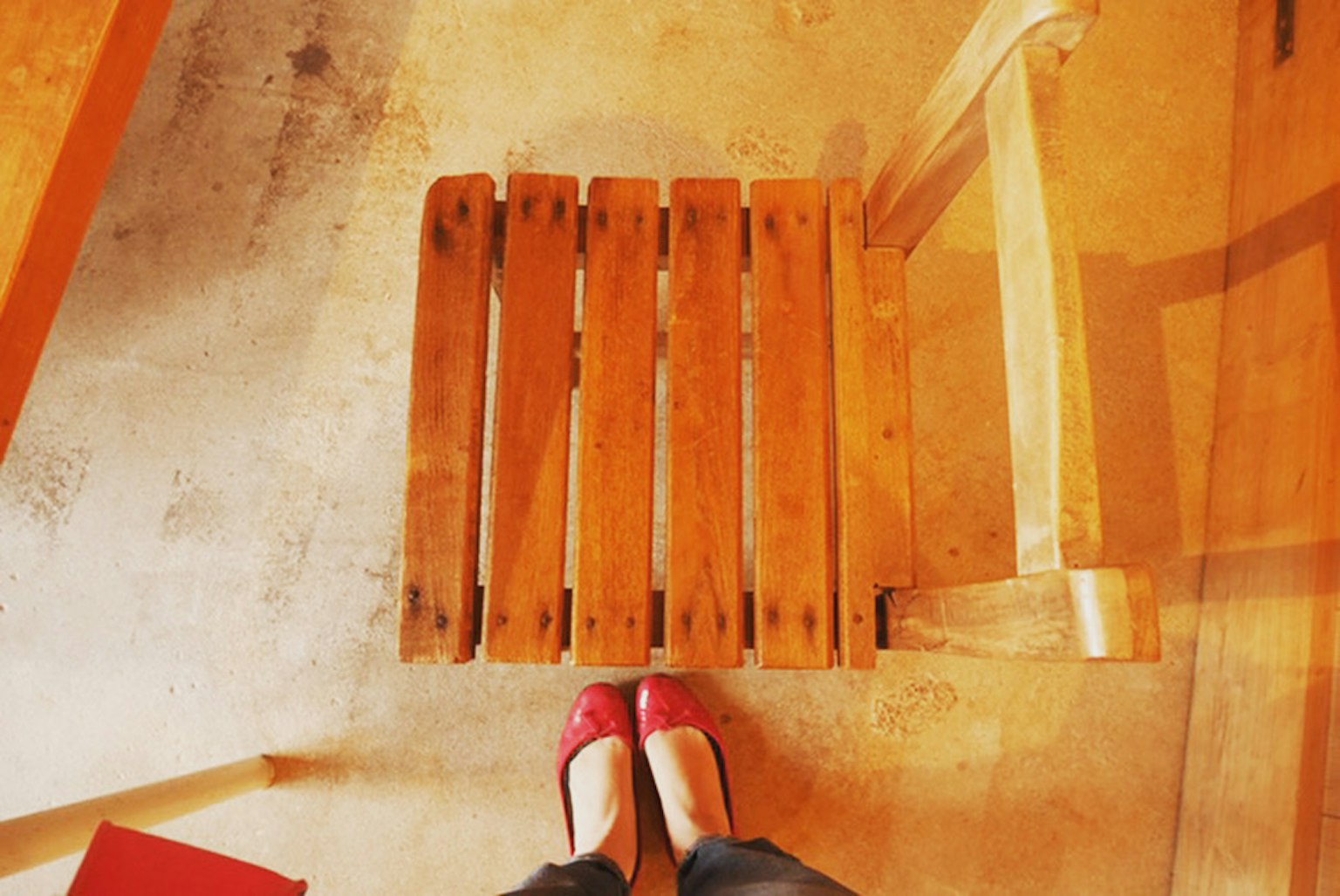 Một người mặc giày đỏ đứng trên ghế gỗ từ góc nhìn trên cao