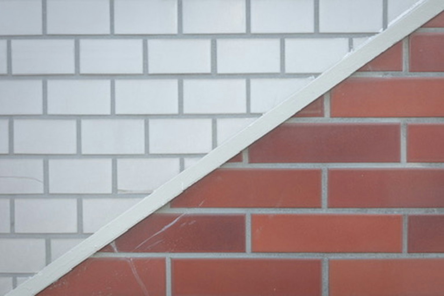 Mur divisé en diagonale avec des carreaux blancs d'un côté et des carreaux rouges de l'autre