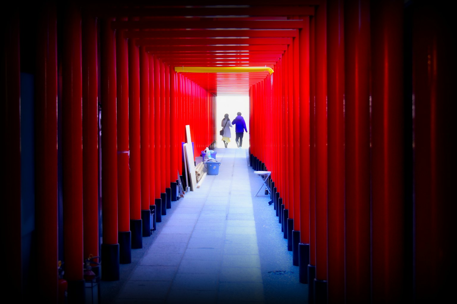 Des personnes marchant à travers un tunnel bordé de portes torii rouges