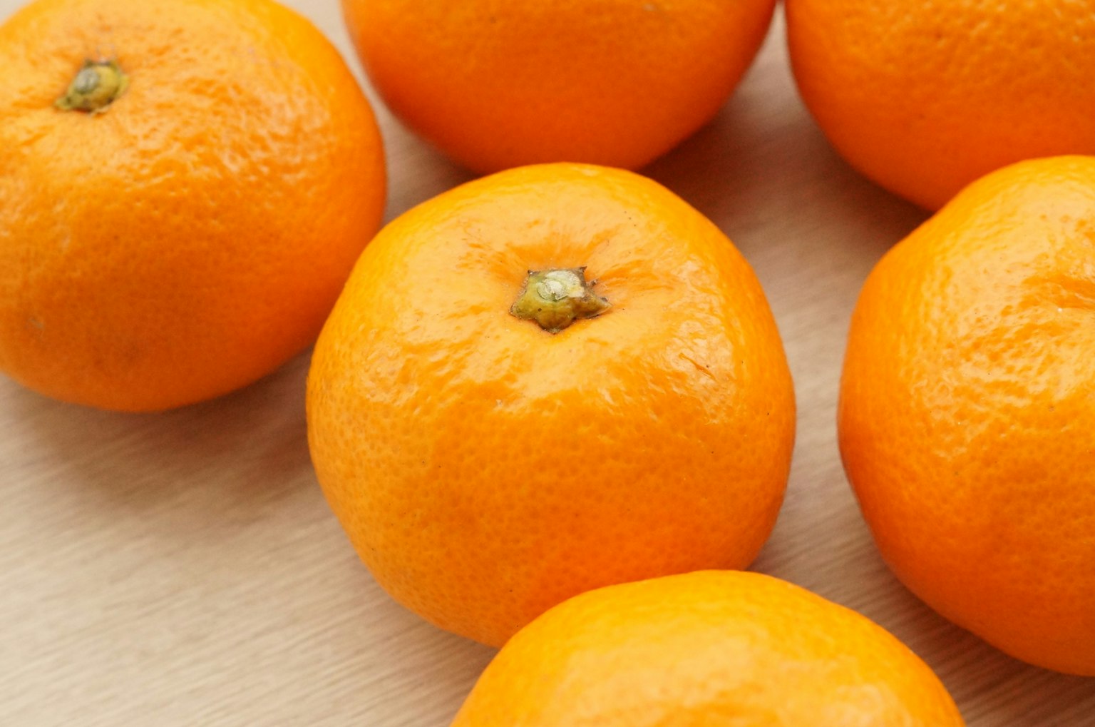 Beberapa jeruk mandarin oranye cerah disusun di atas permukaan kayu