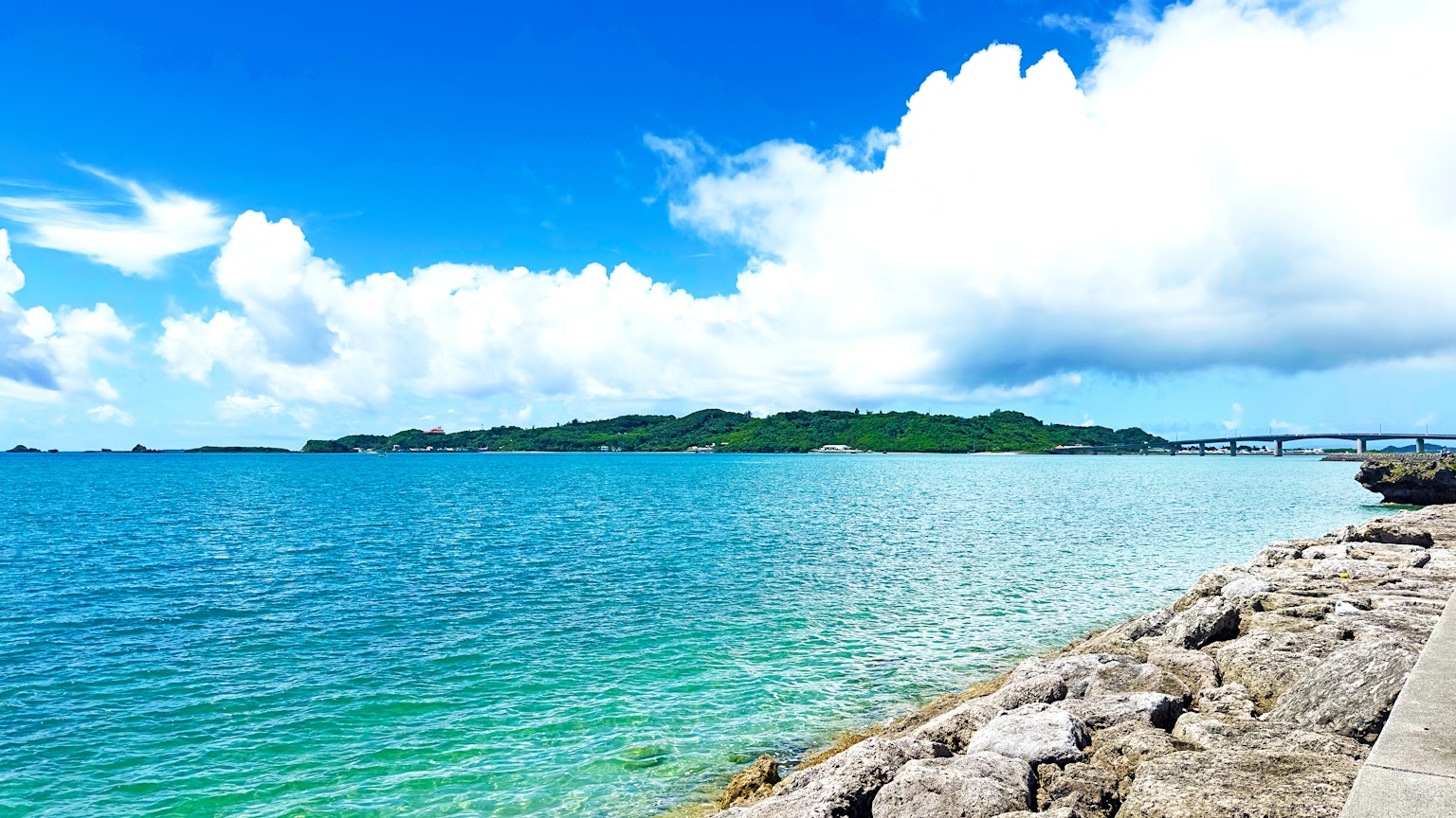 藍色海洋和白色雲朵的風景 岩石海岸和綠色島嶼可見