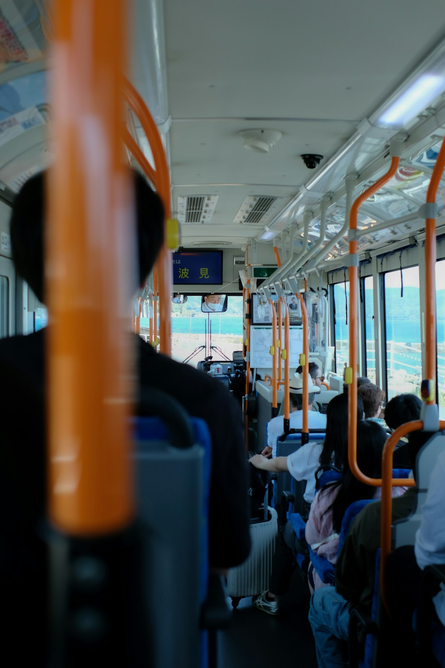 Vista interna di un autobus con passeggeri e pali di supporto arancioni