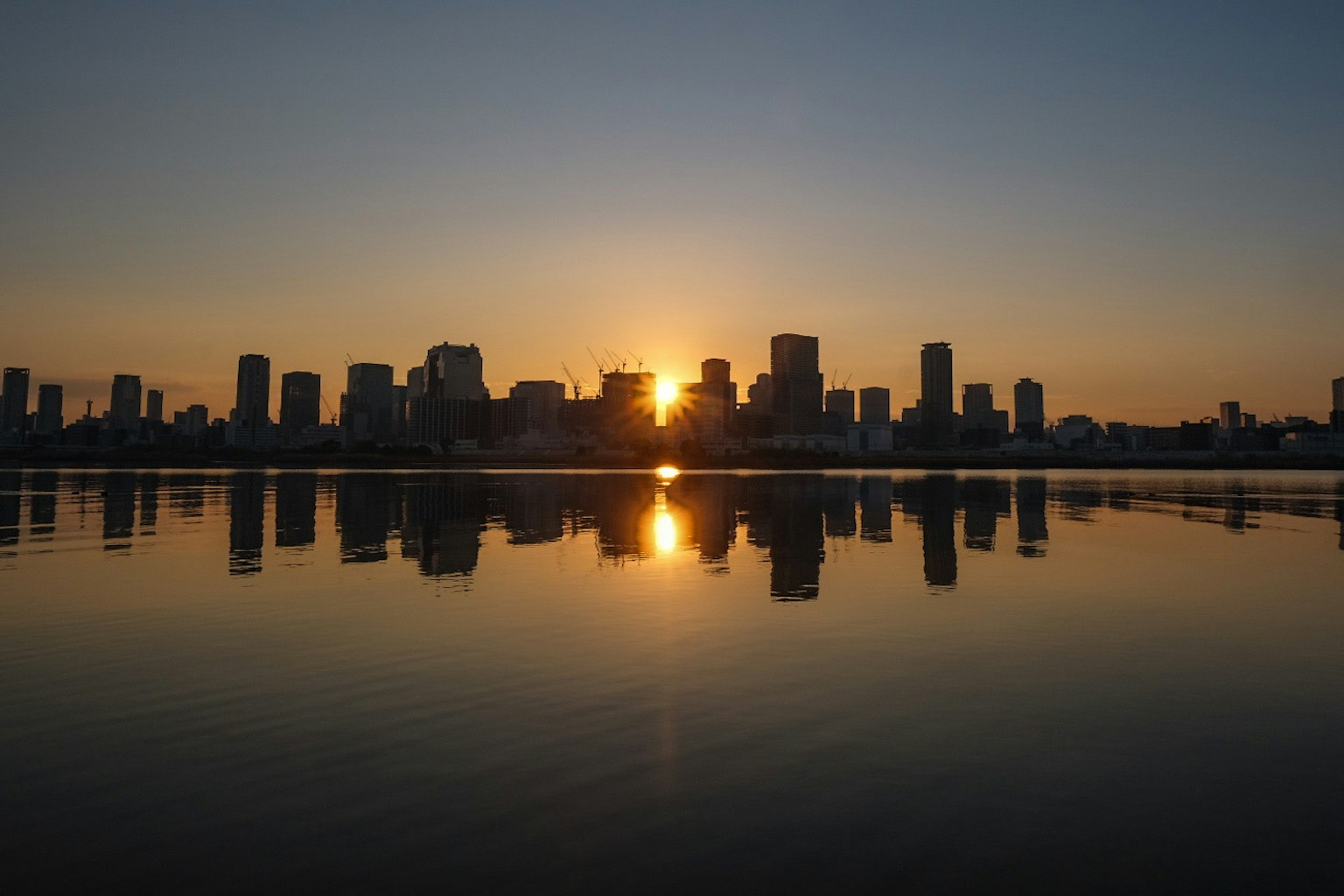 Silhouette de la ville au coucher du soleil réfléchissant sur l'eau
