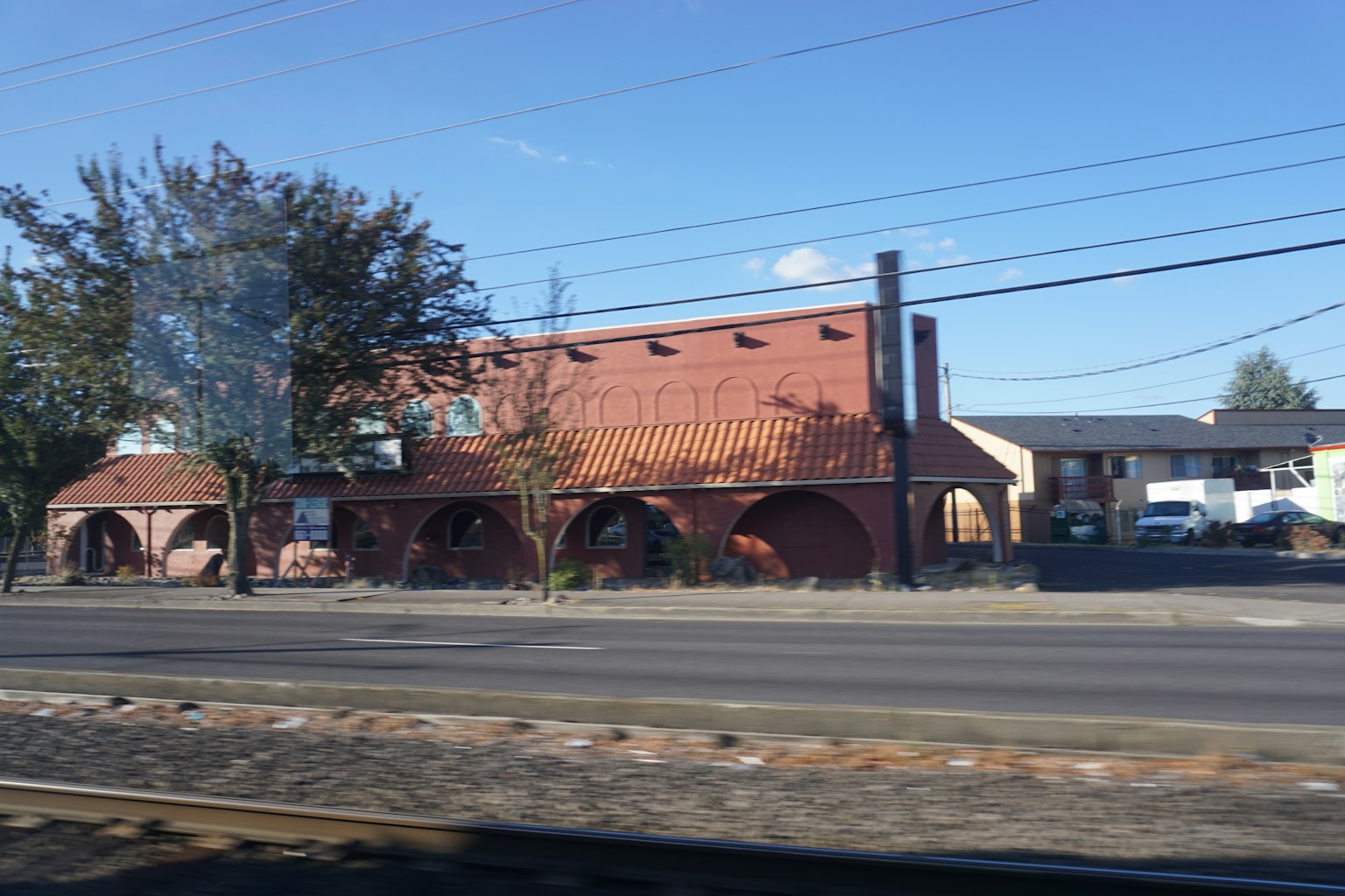 Red brick building with arched windows and nearby trees