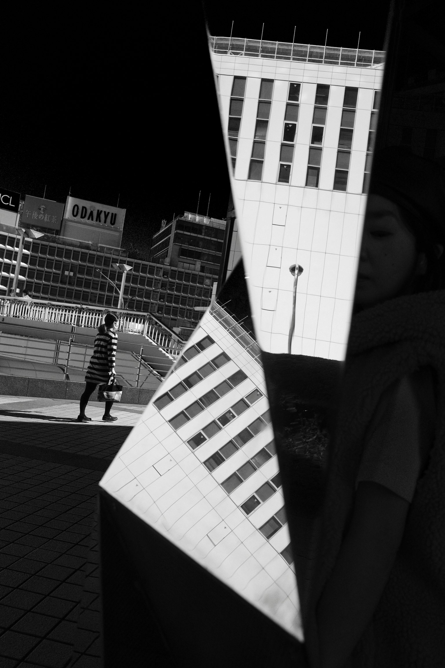 Black and white image showing a reflected building and a silhouette of a person
