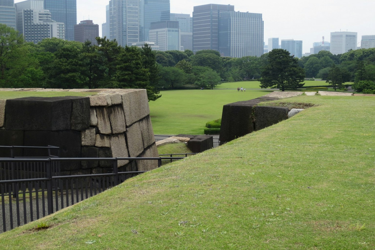 Historic stone structure surrounded by green park with modern city skyline