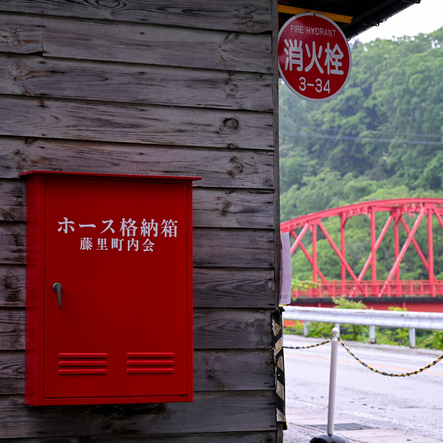 Buzón rojo y puente rojo en una vista escénica pared de madera al fondo
